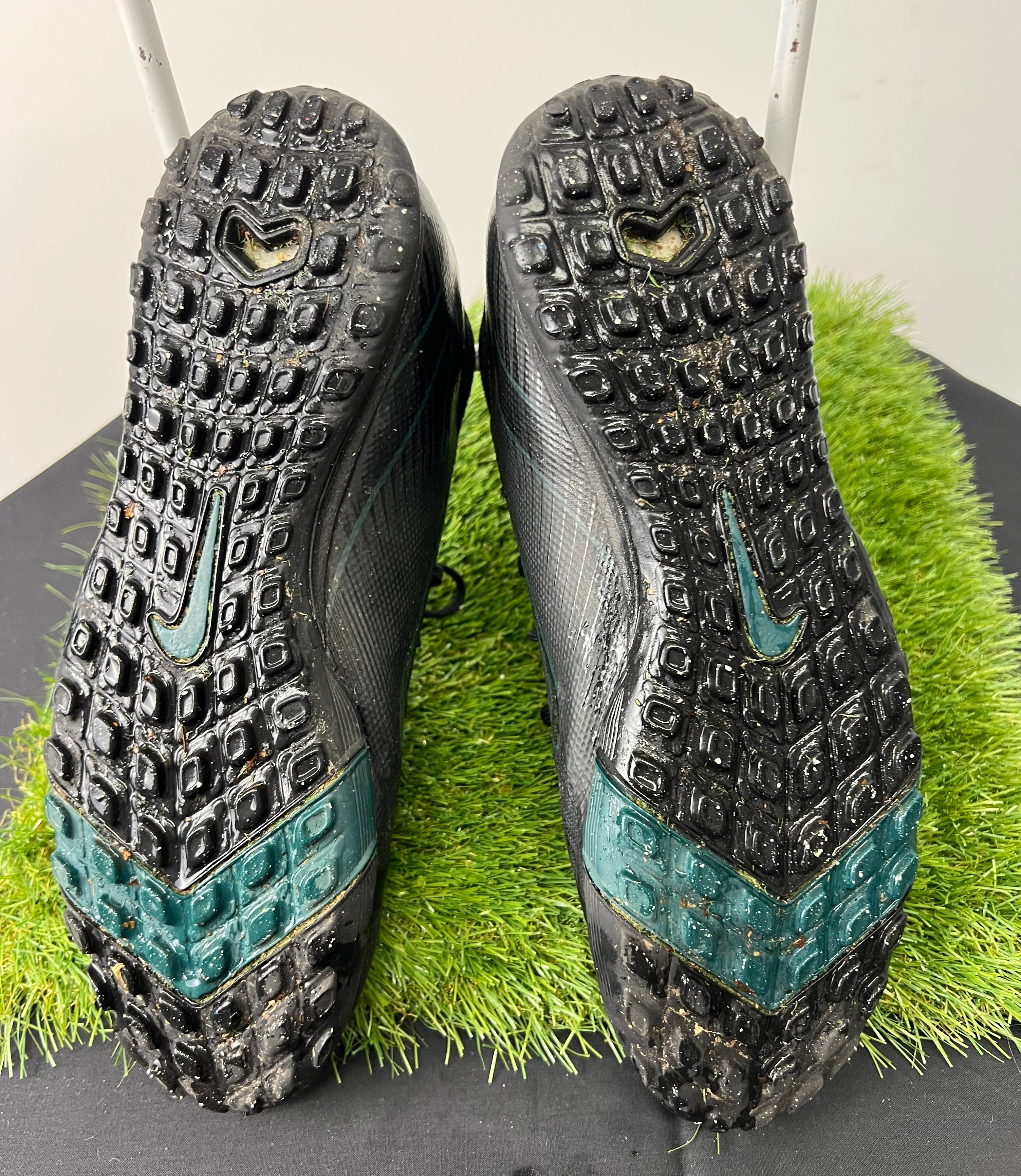 Soles of Nike Astro Turf football boots showing rubber studs and Nike logos, with slight wear