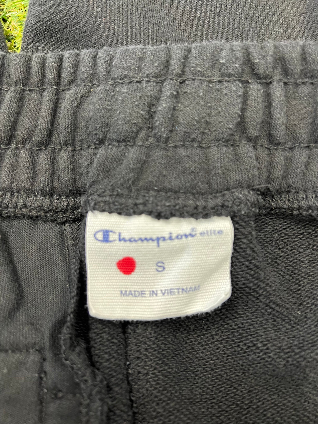 Close-up of Champion brand label inside waistband showing size Small and made in Vietnam