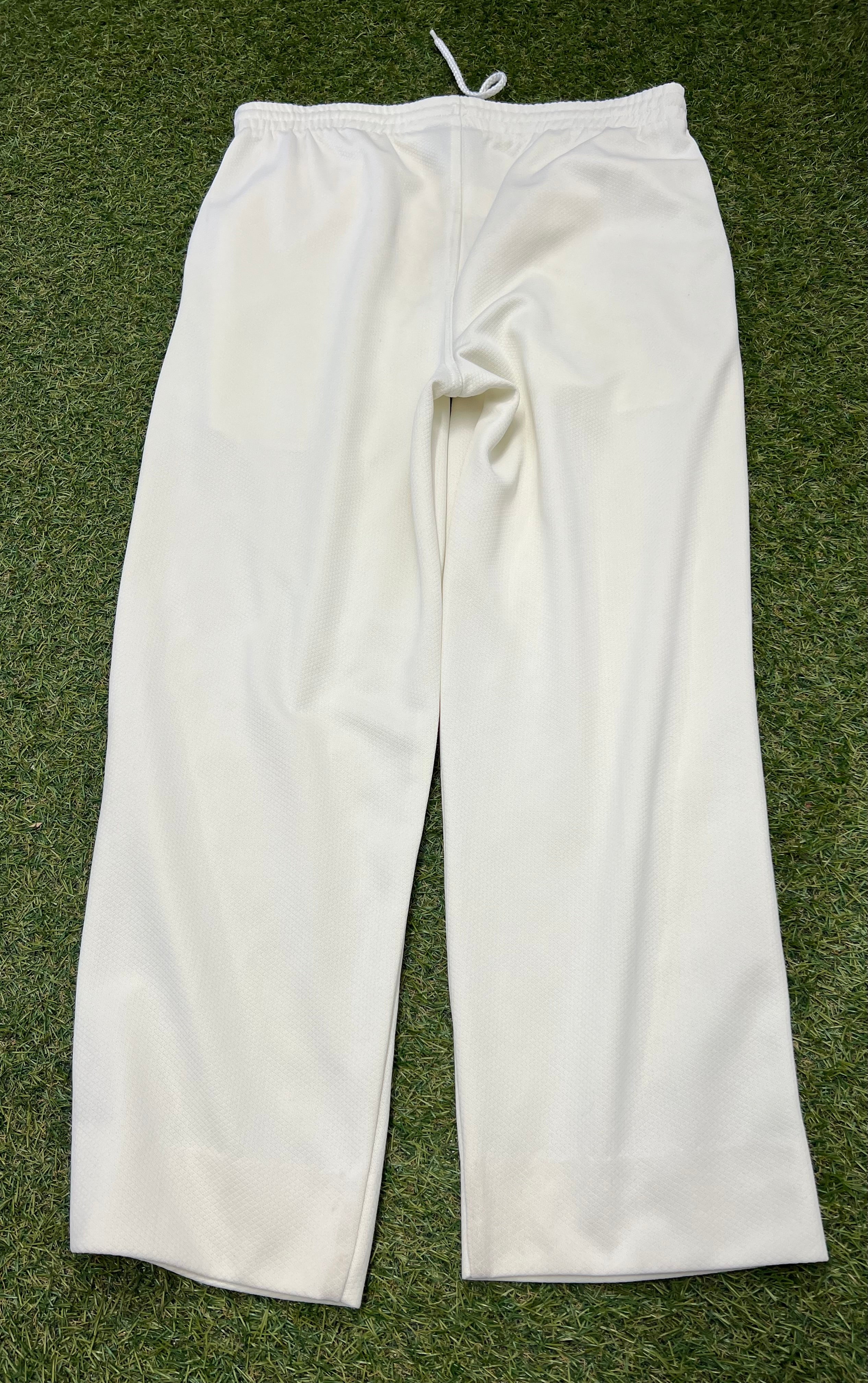 Back view of white Slazenger cricket trousers on grass background