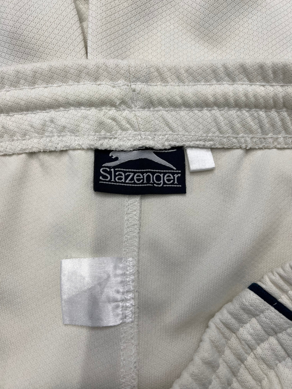 Close-up of Slazenger brand label inside waistband of white cricket trousers
