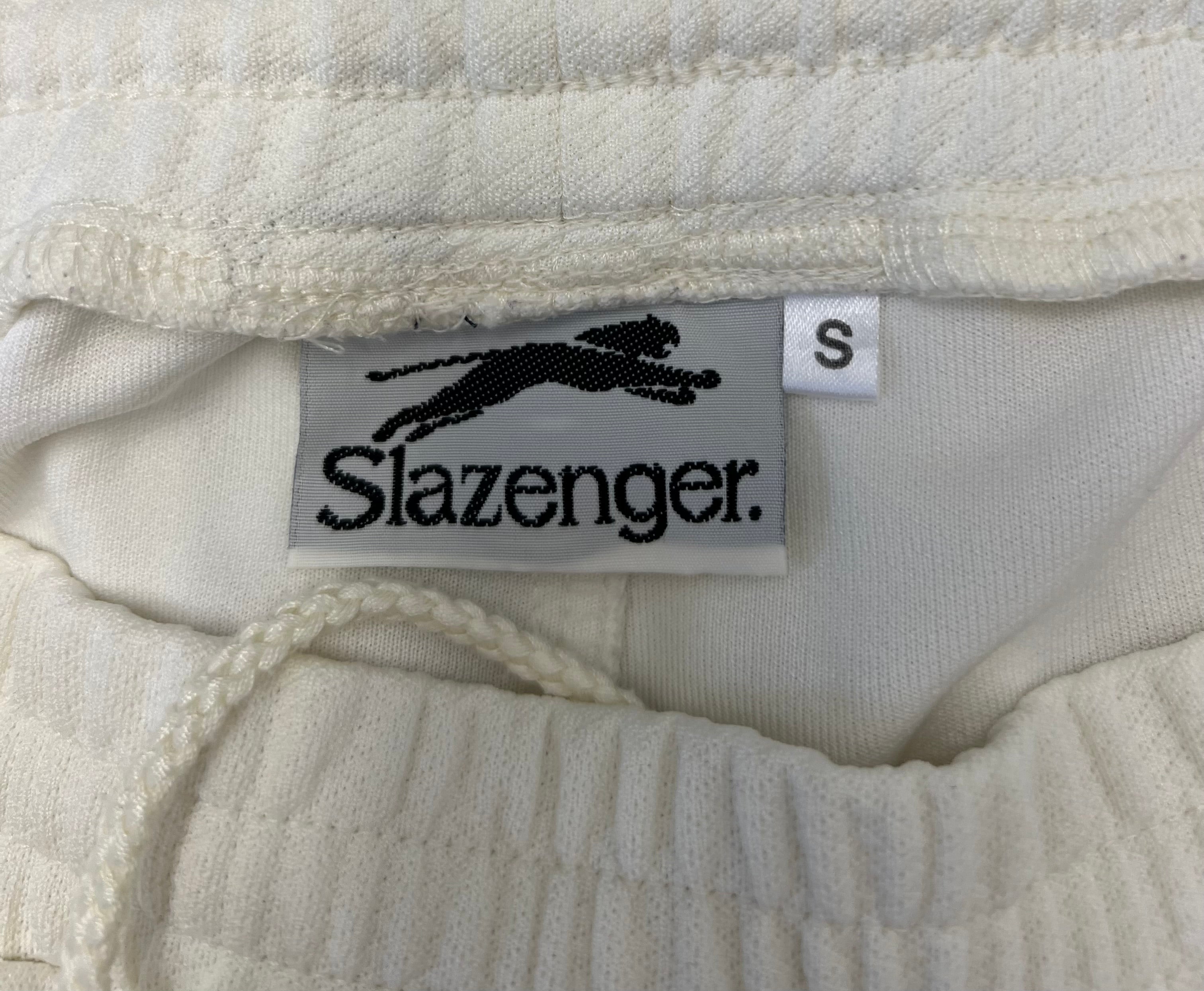 Close-up of Slazenger brand label and elastic waistband with drawstring on white cricket trousers