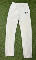 Front view of Slazenger kids white cricket trousers laid flat on grass