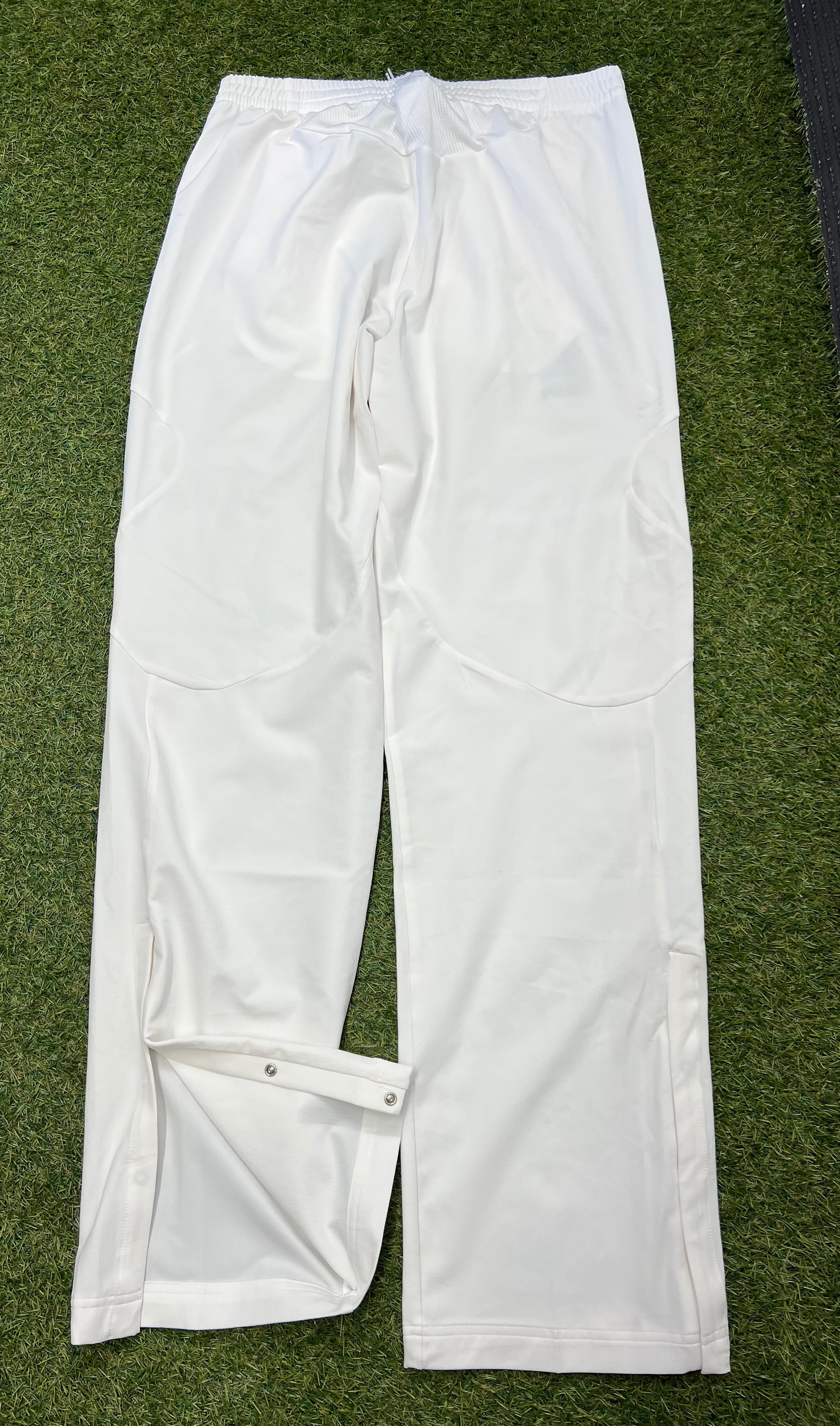 Back view of men's white Adidas cricket trousers showing snap-button openings at leg hems