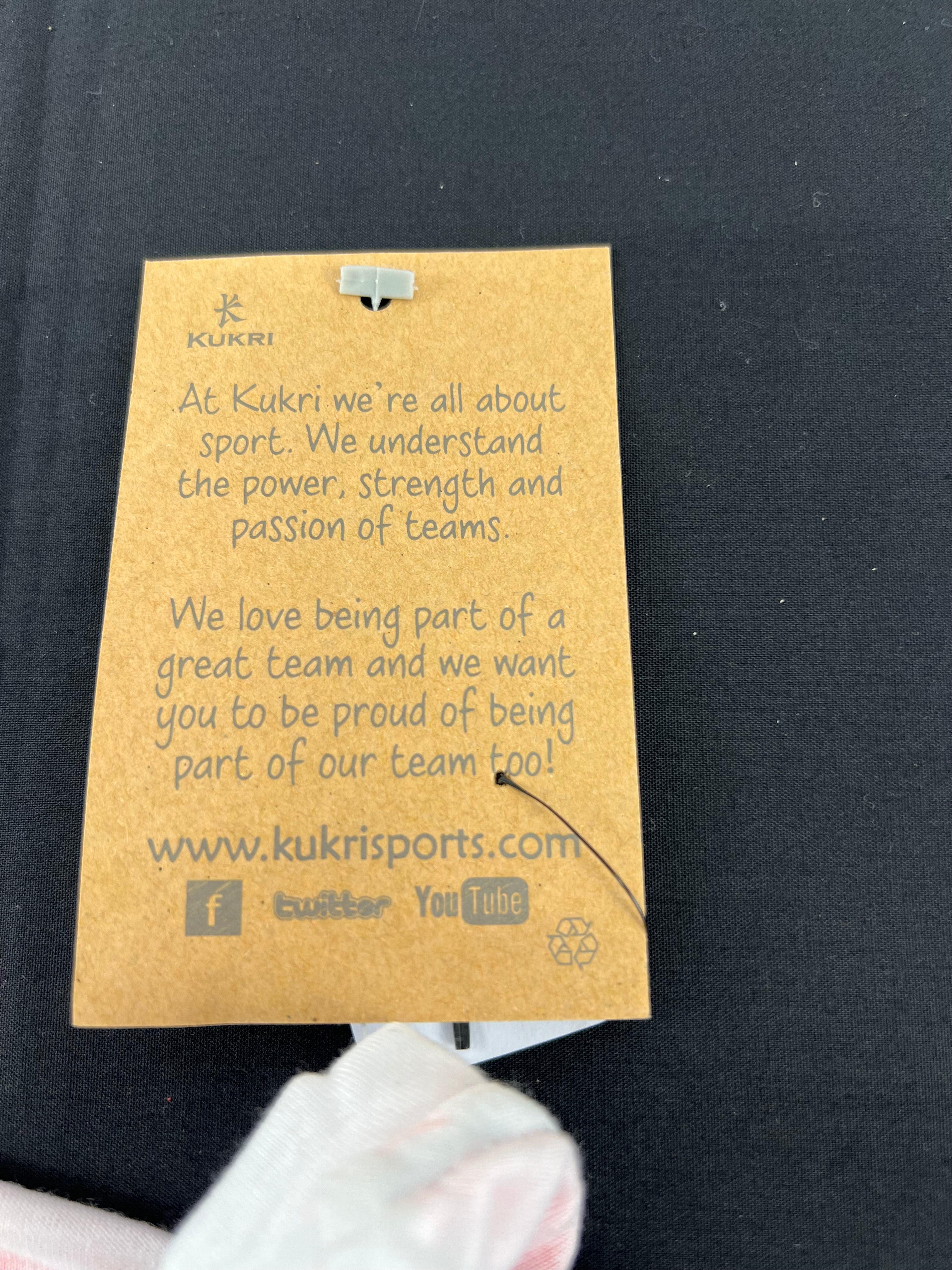 Brown Kukri tag with motivational text about sport and team spirit attached to the t-shirt