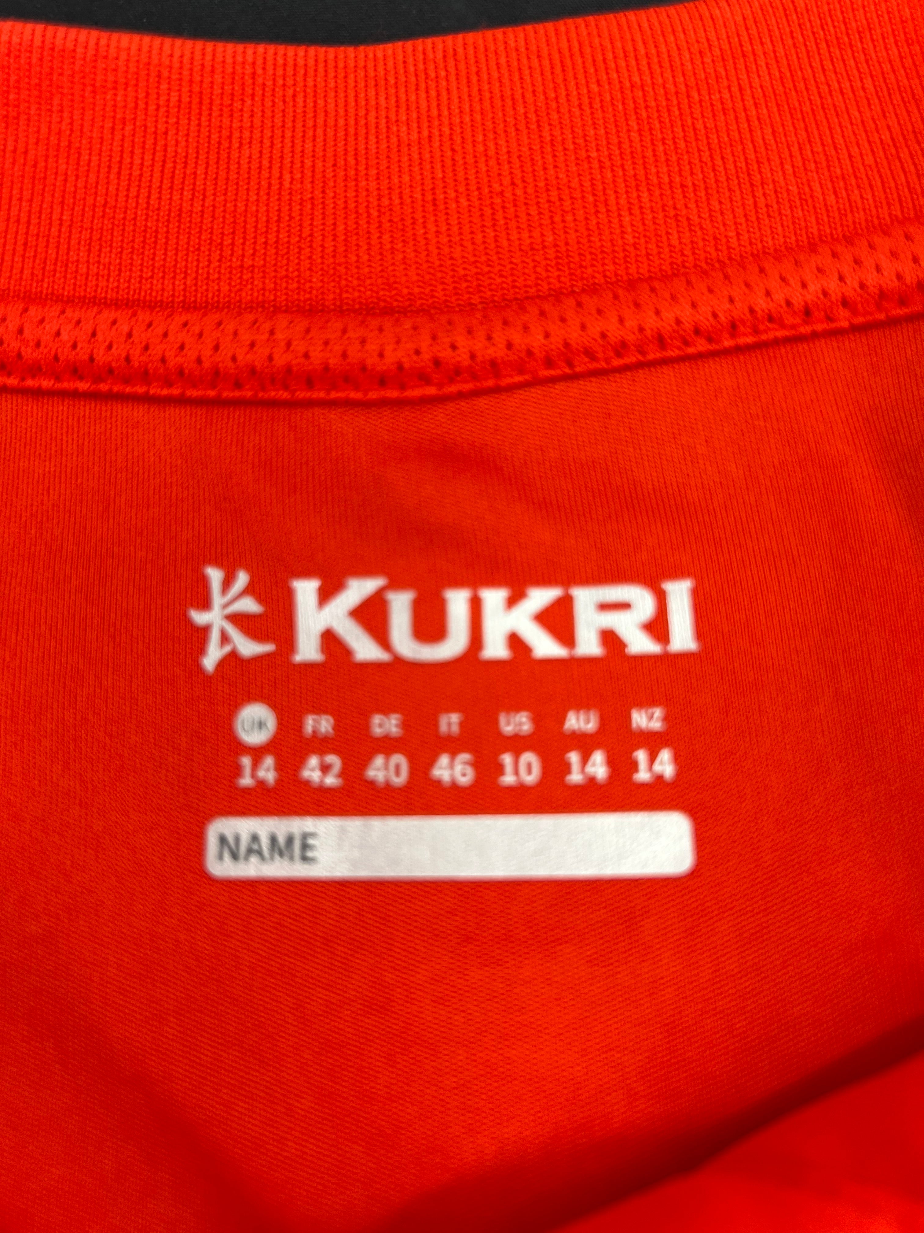 Close-up of printed Kukri size and name tag inside collar of red polo shirt