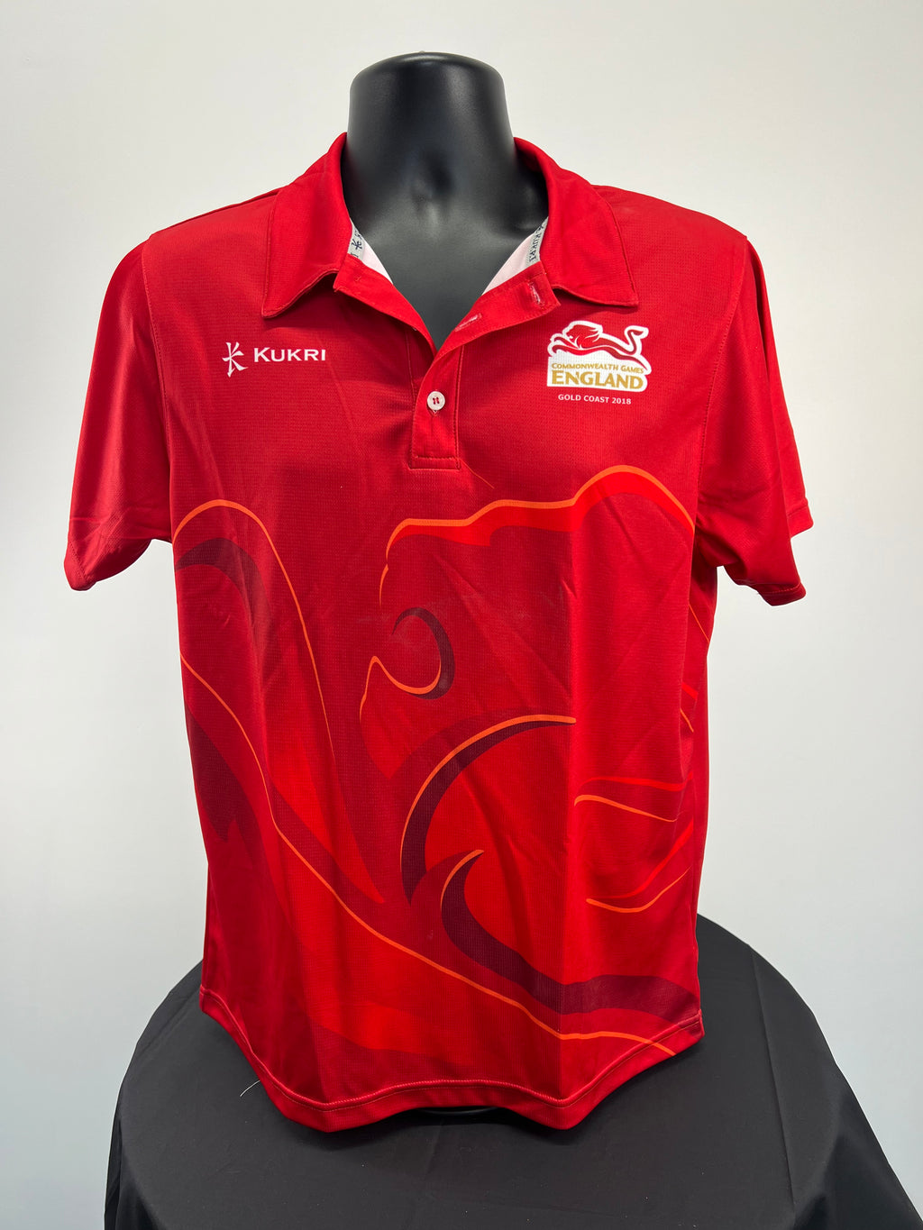 Front view of red Kukri polo shirt with Commonwealth Games England logo and large lion graphic