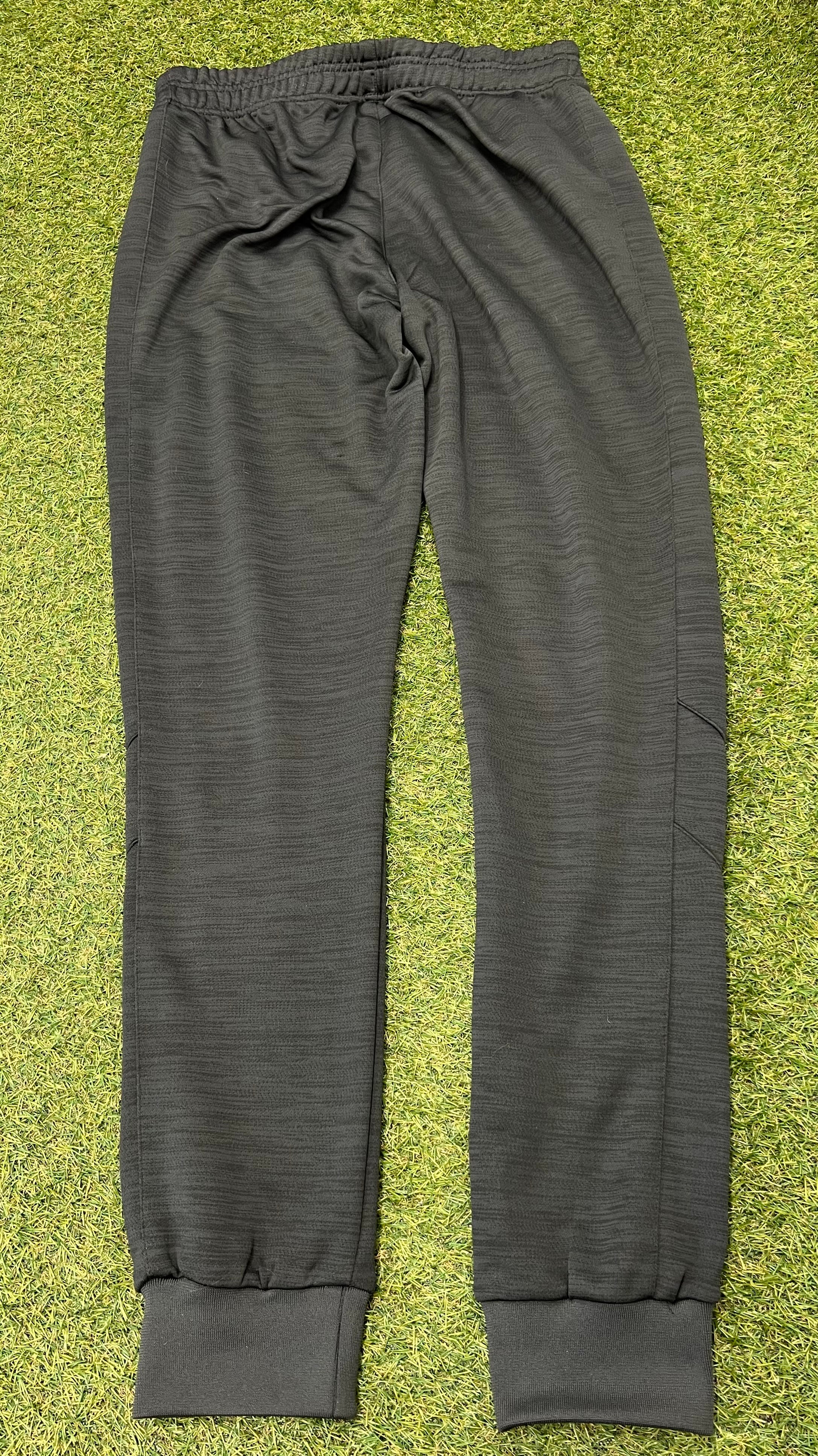 Back view of dark grey Kukri women's tracksuit bottoms showing ribbed cuffs on grass