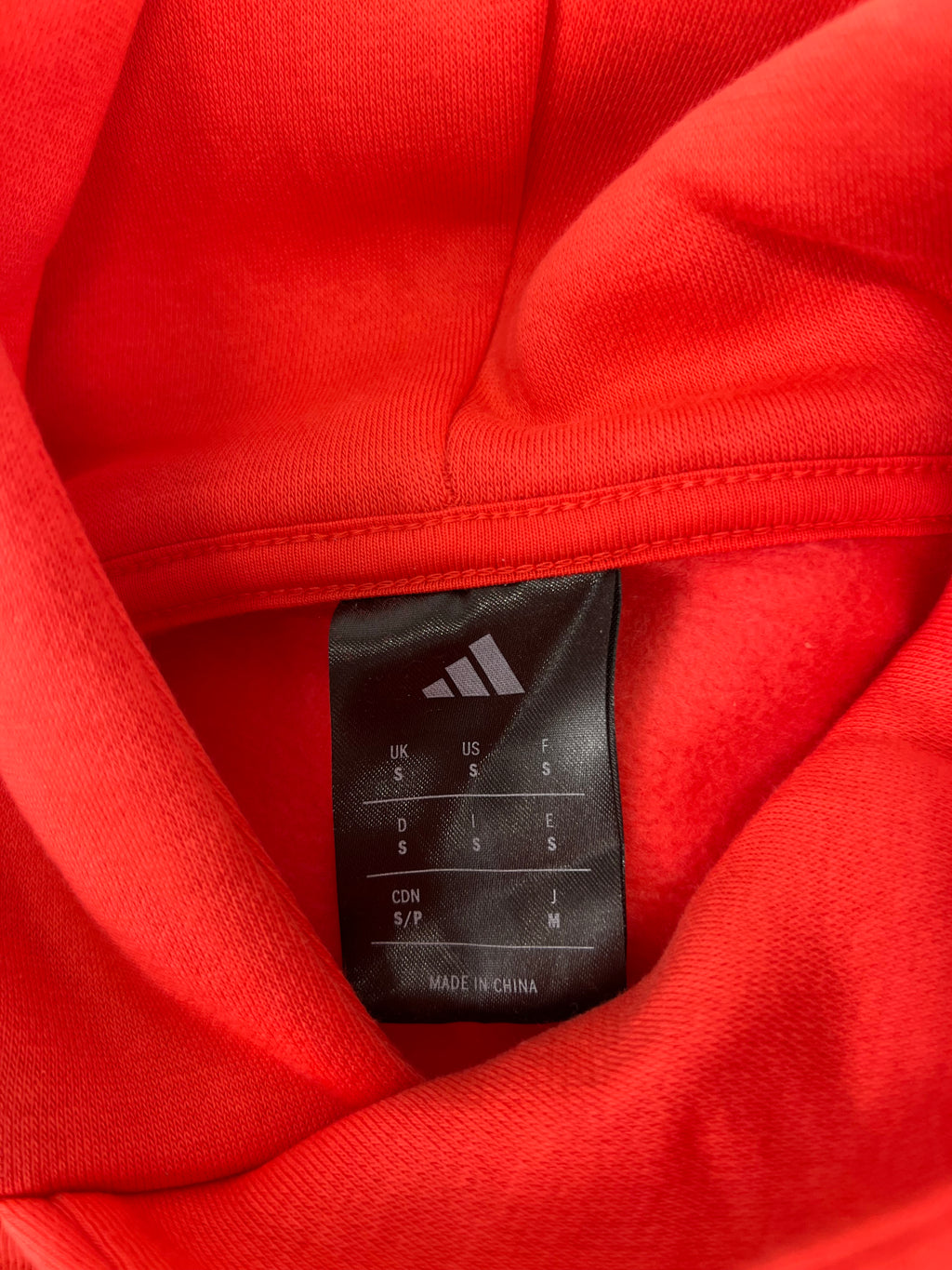 Label inside Adidas hoodie showing size small and made in China