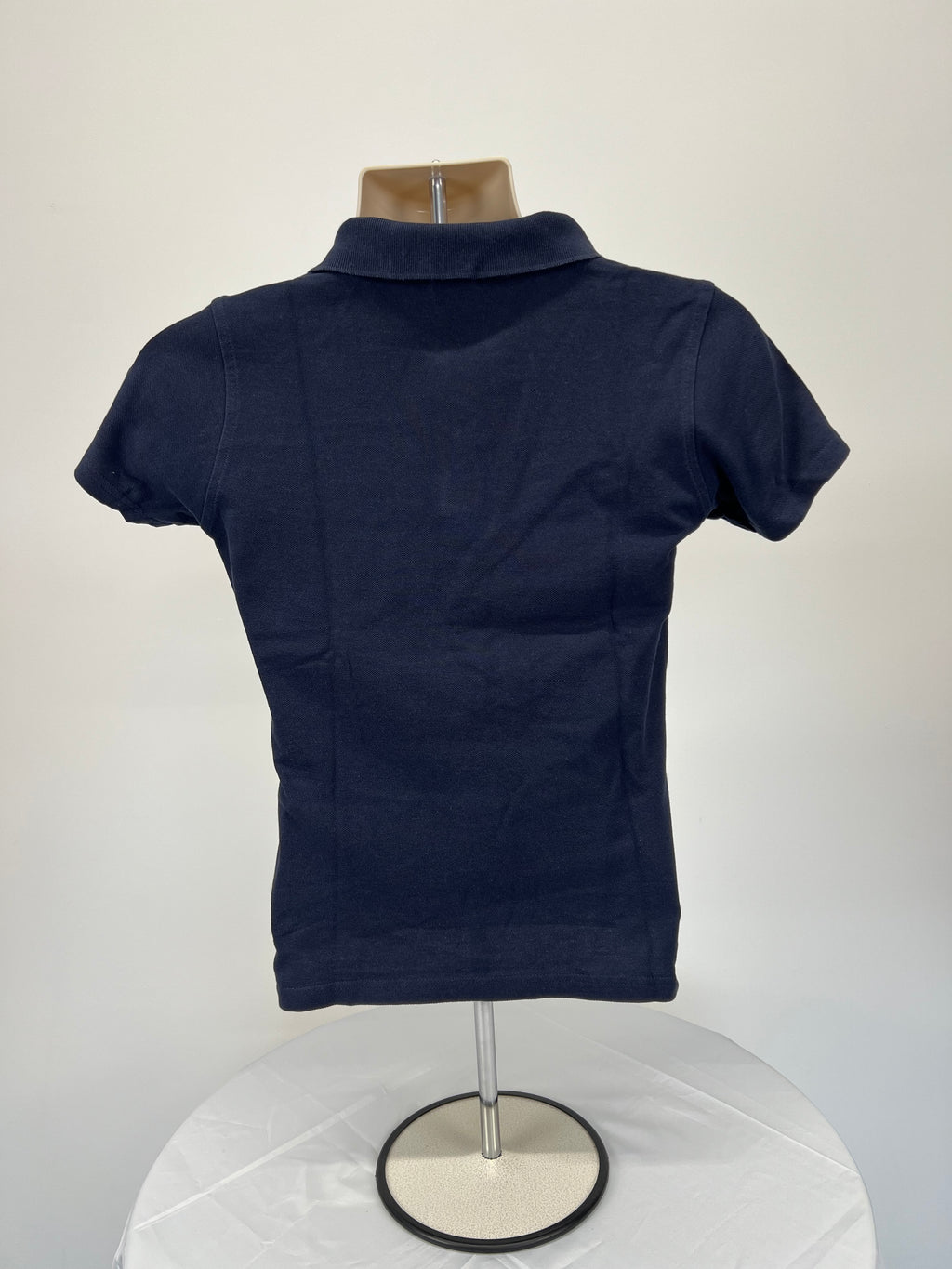 Back view of navy blue women’s polo shirt showing plain design with short sleeves and collar