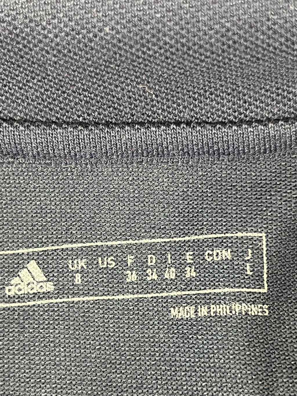 Close-up of Adidas size label inside the navy blue polo shirt showing UK size 8 and made in Philippines