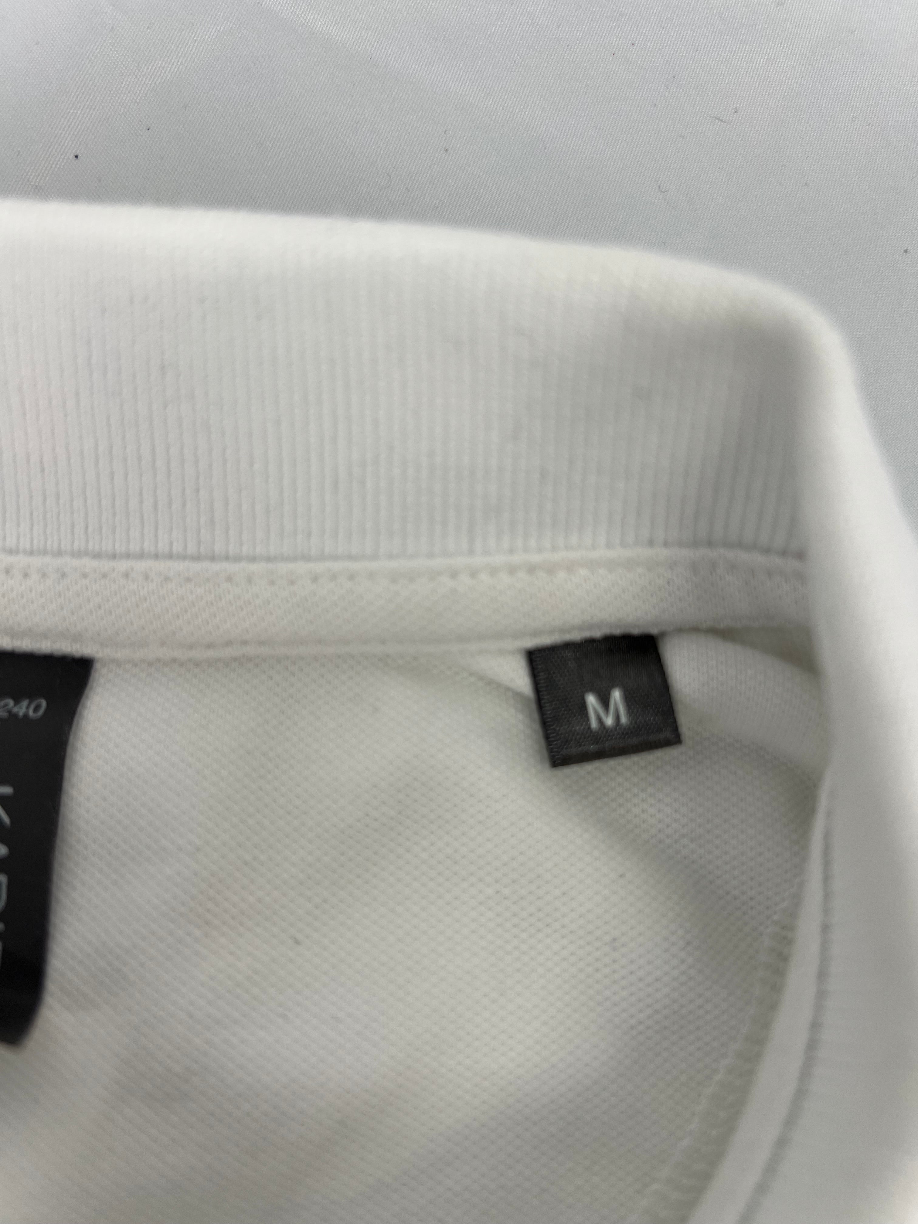 Close-up of collar and size tag marked medium on women’s white polo shirt