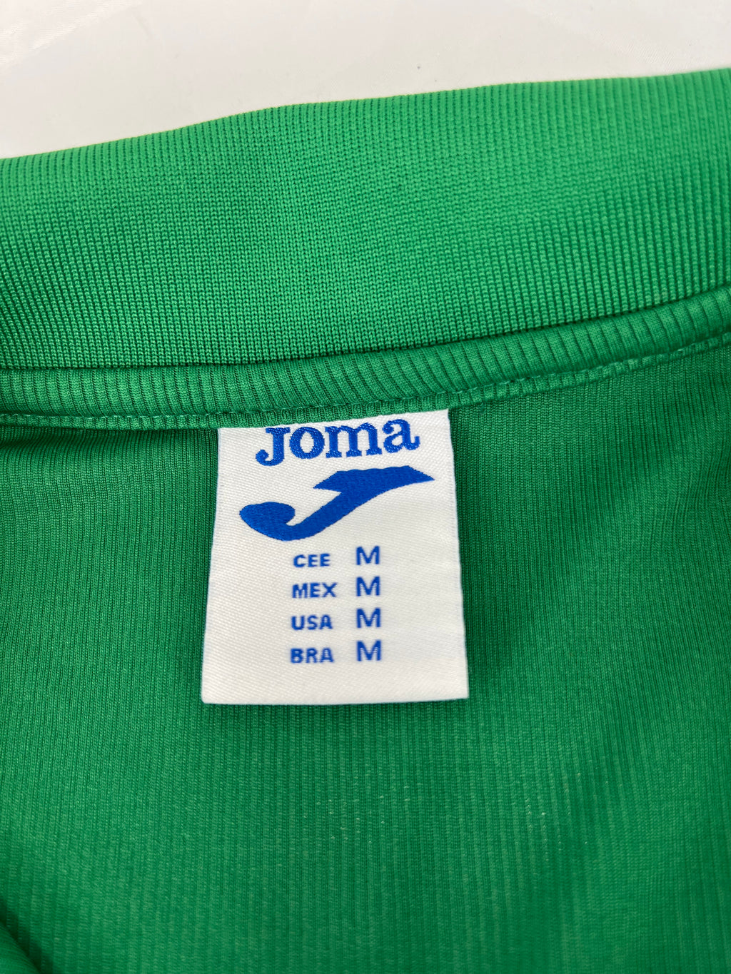 Close-up of Joma brand label inside the collar showing size medium in various country standards