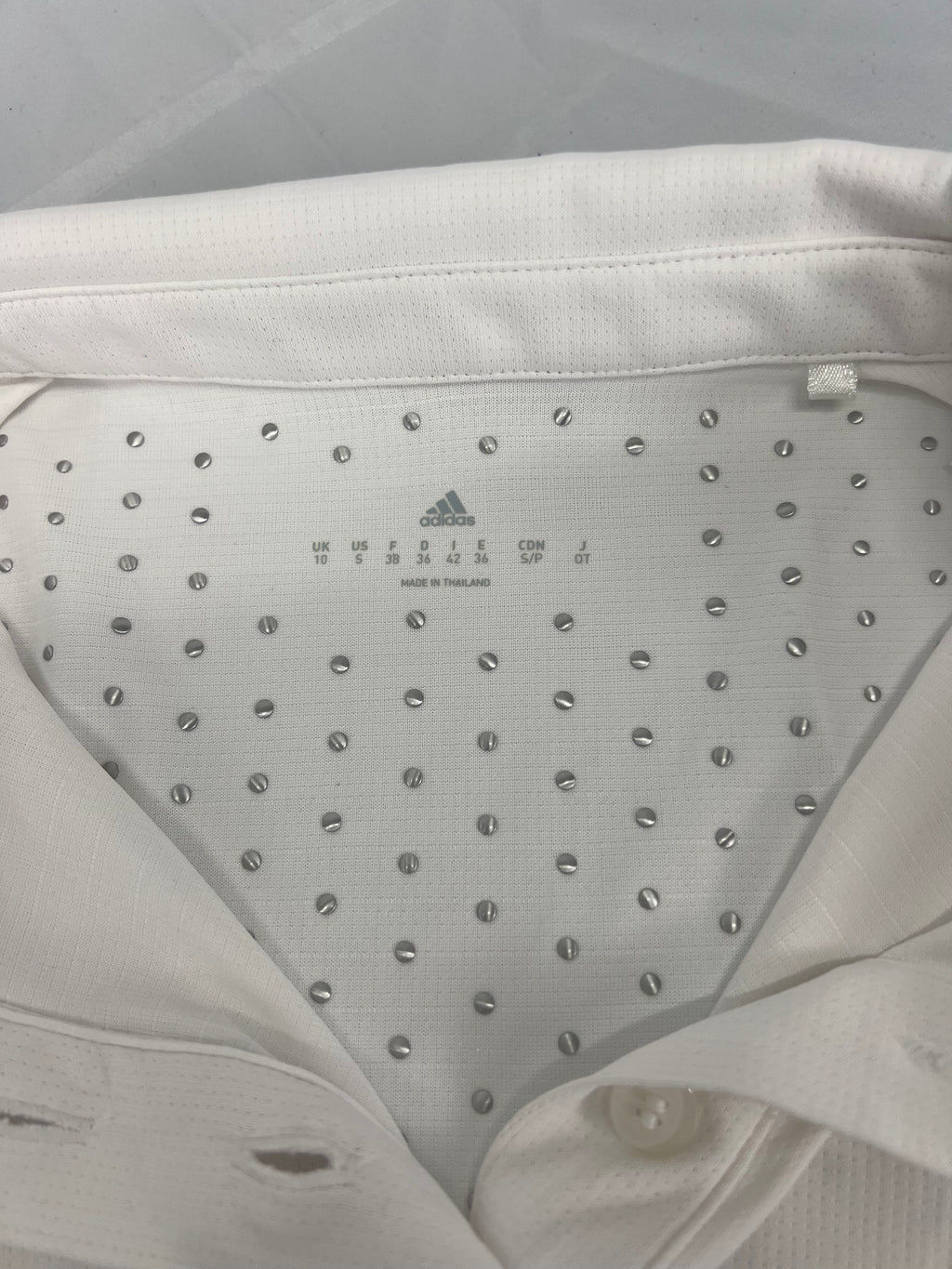 Close-up inside collar of polo top showing anti-slip silicone dots and size details