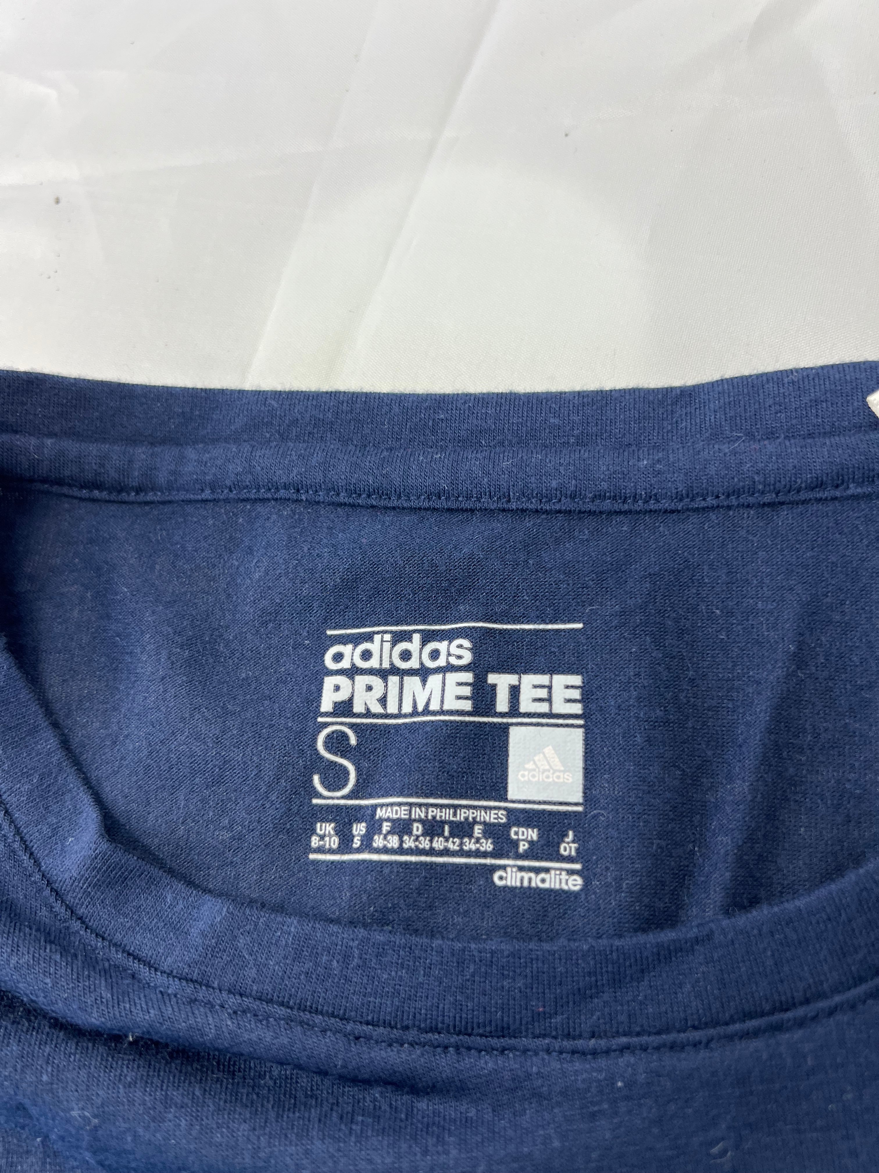 Close-up of adidas Prime Tee label and size information inside neckline