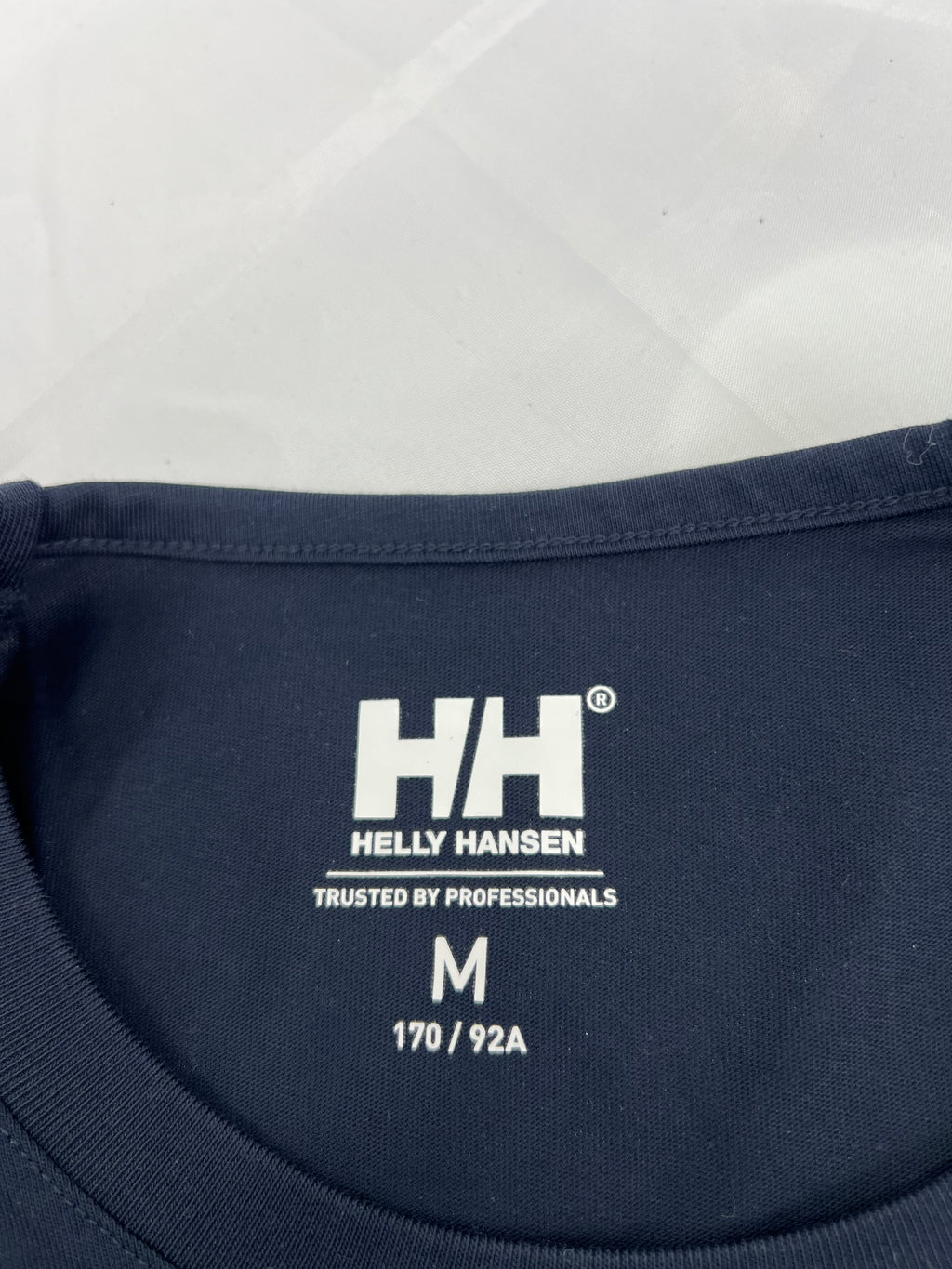 Close-up of inside neck label of Helly Hansen t-shirt with size medium and Trusted by Professionals tagline