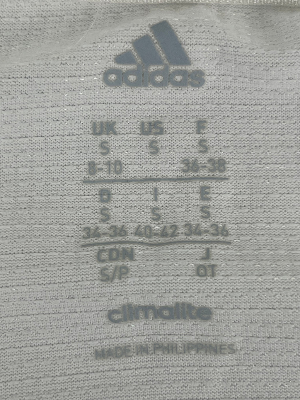 Close-up of adidas size label and Climalite fabric detail on women's long sleeve top