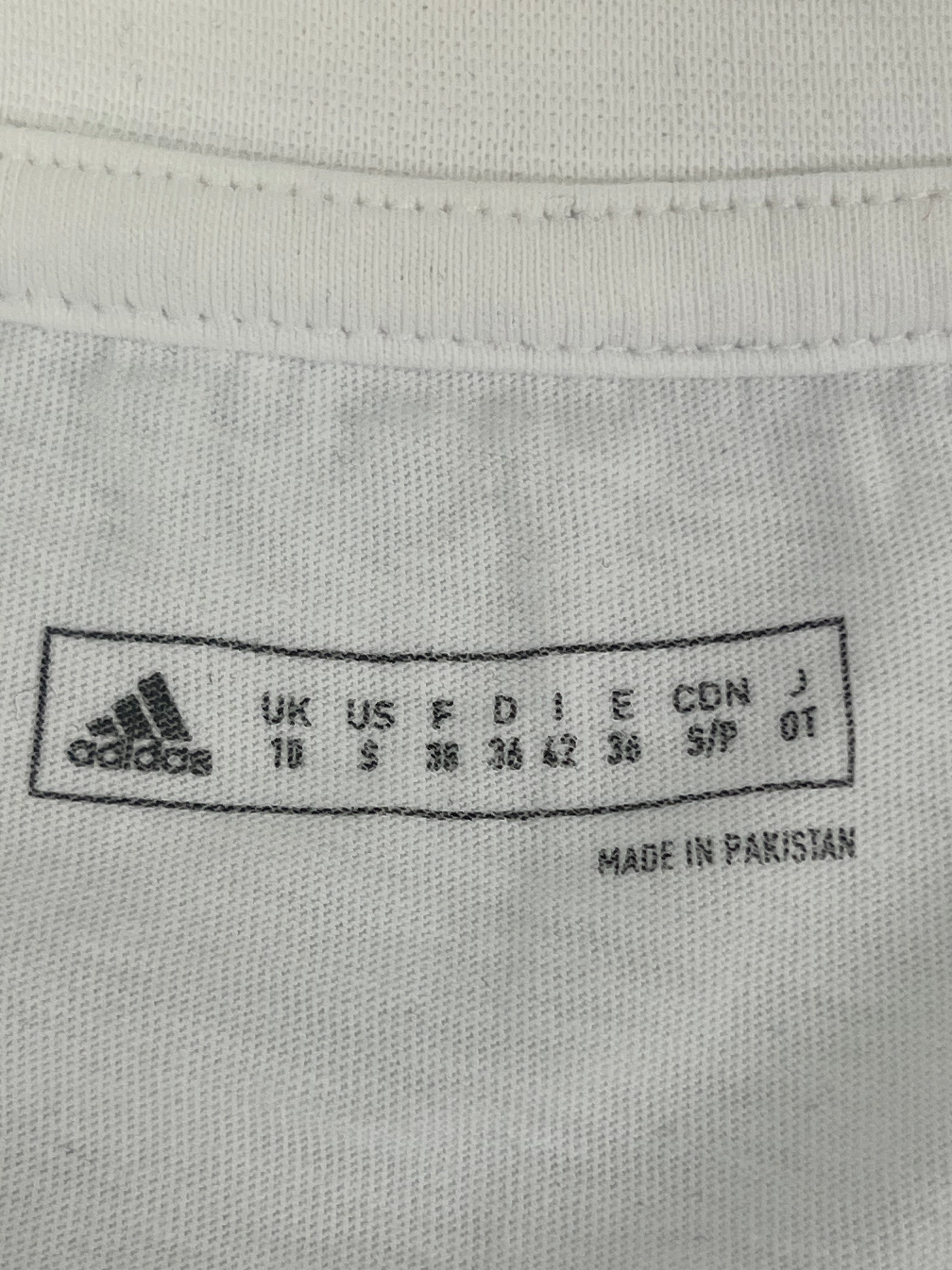 Inside neck label showing Adidas sizing and made in Pakistan on white women's T-shirt