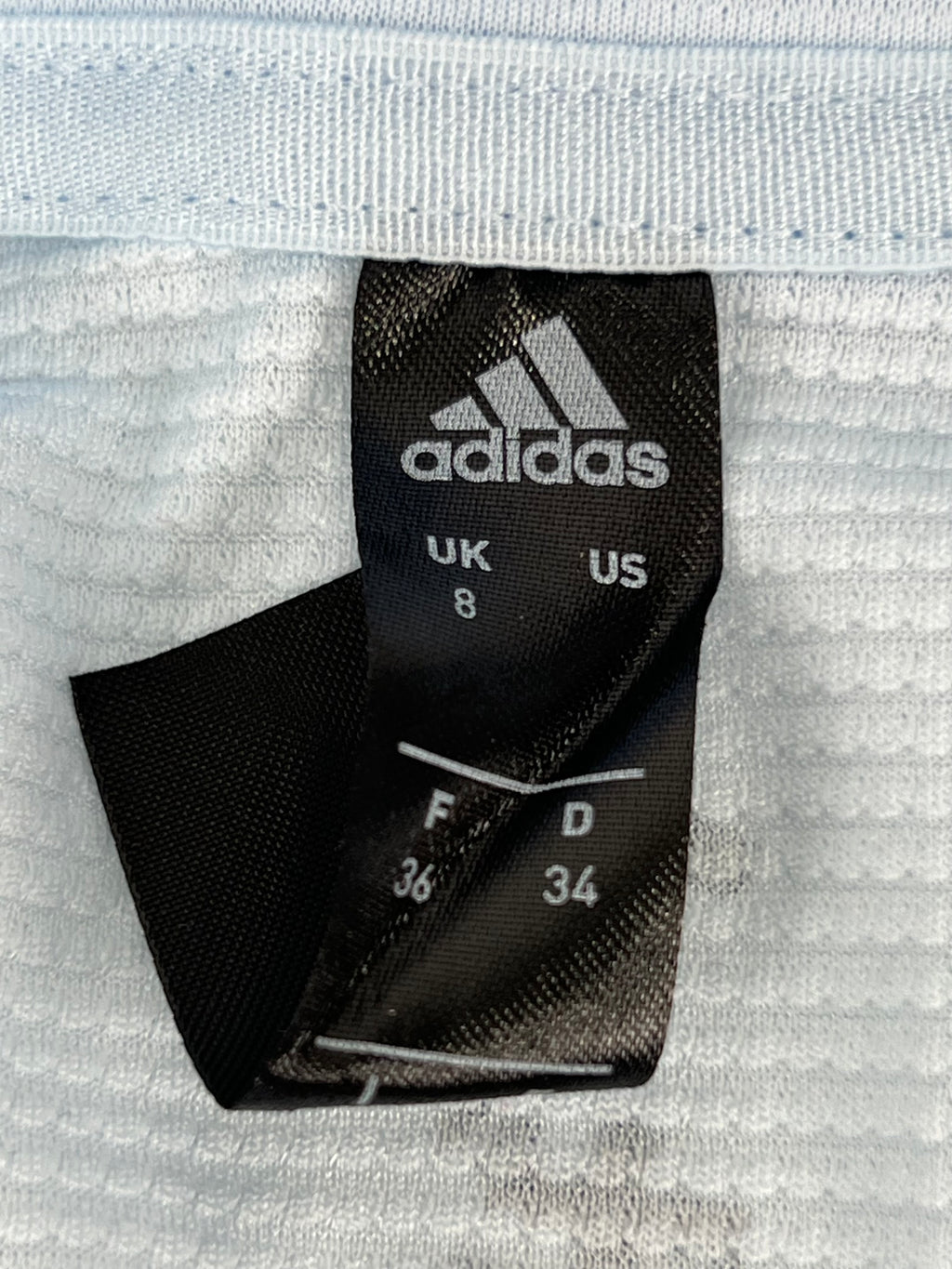adidas size tag showing UK size 8 and US size 4 on inside of light blue Team GB long sleeve top