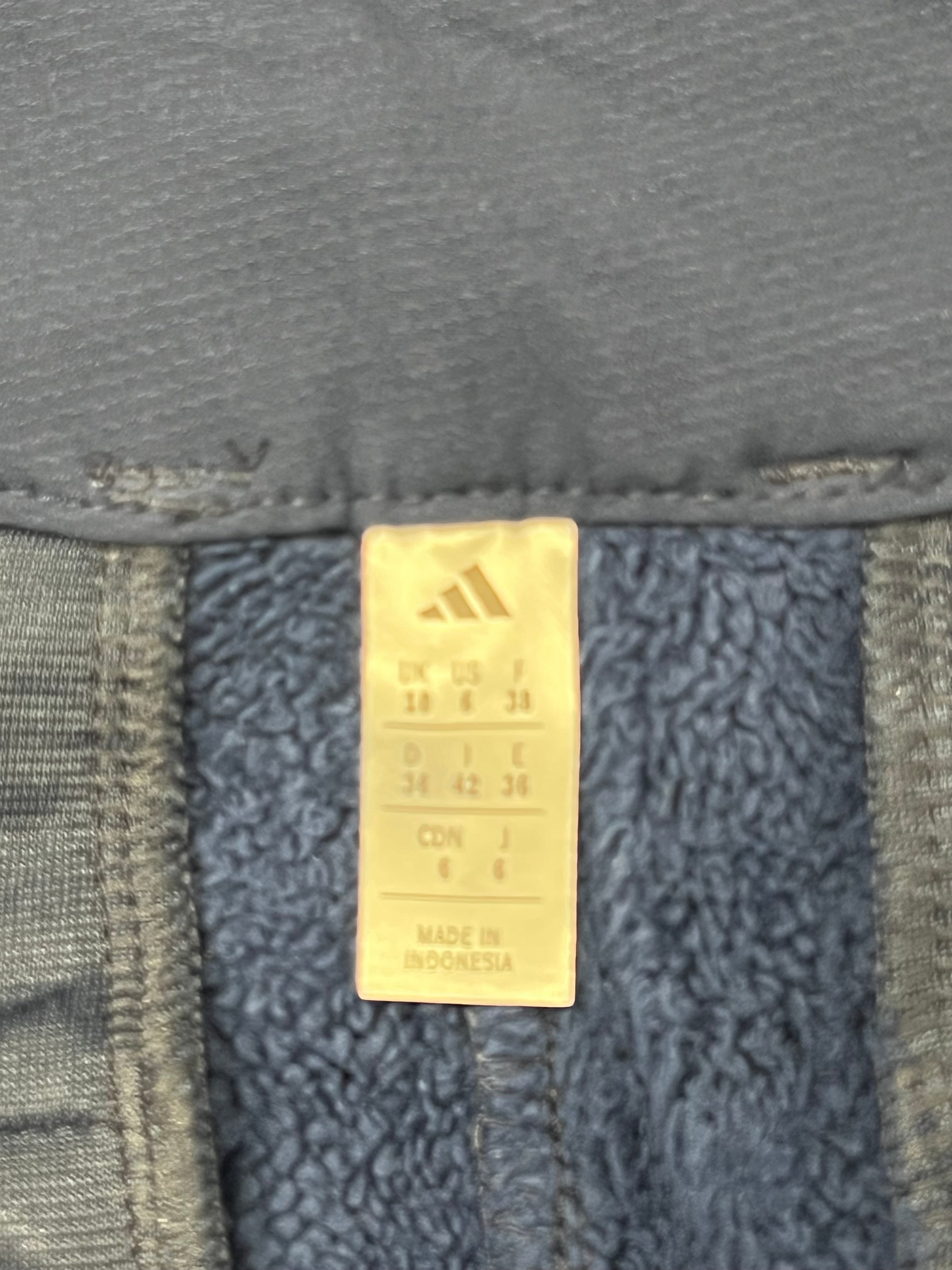 Close-up of Adidas tag inside navy fleece-lined trousers showing sizes and quality