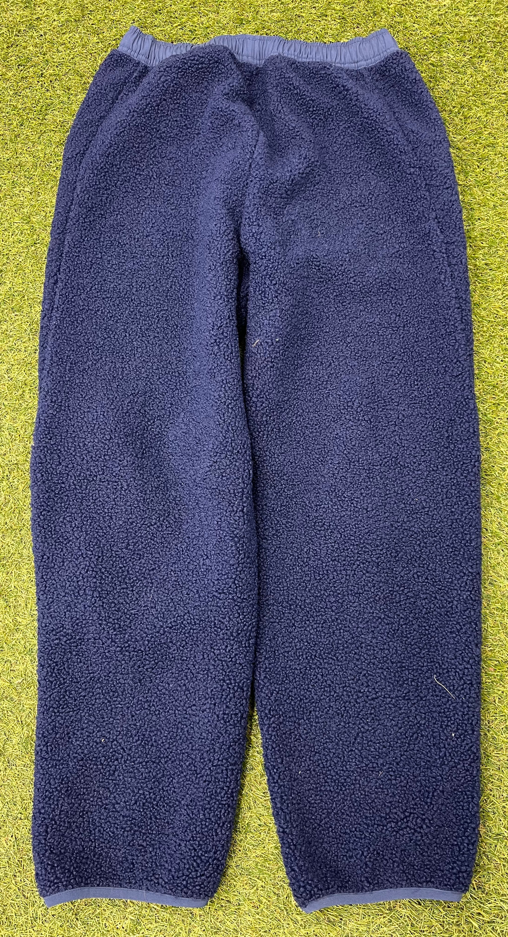 Back view of navy adidas fleece trousers showing elasticated waistband and ankle cuffs