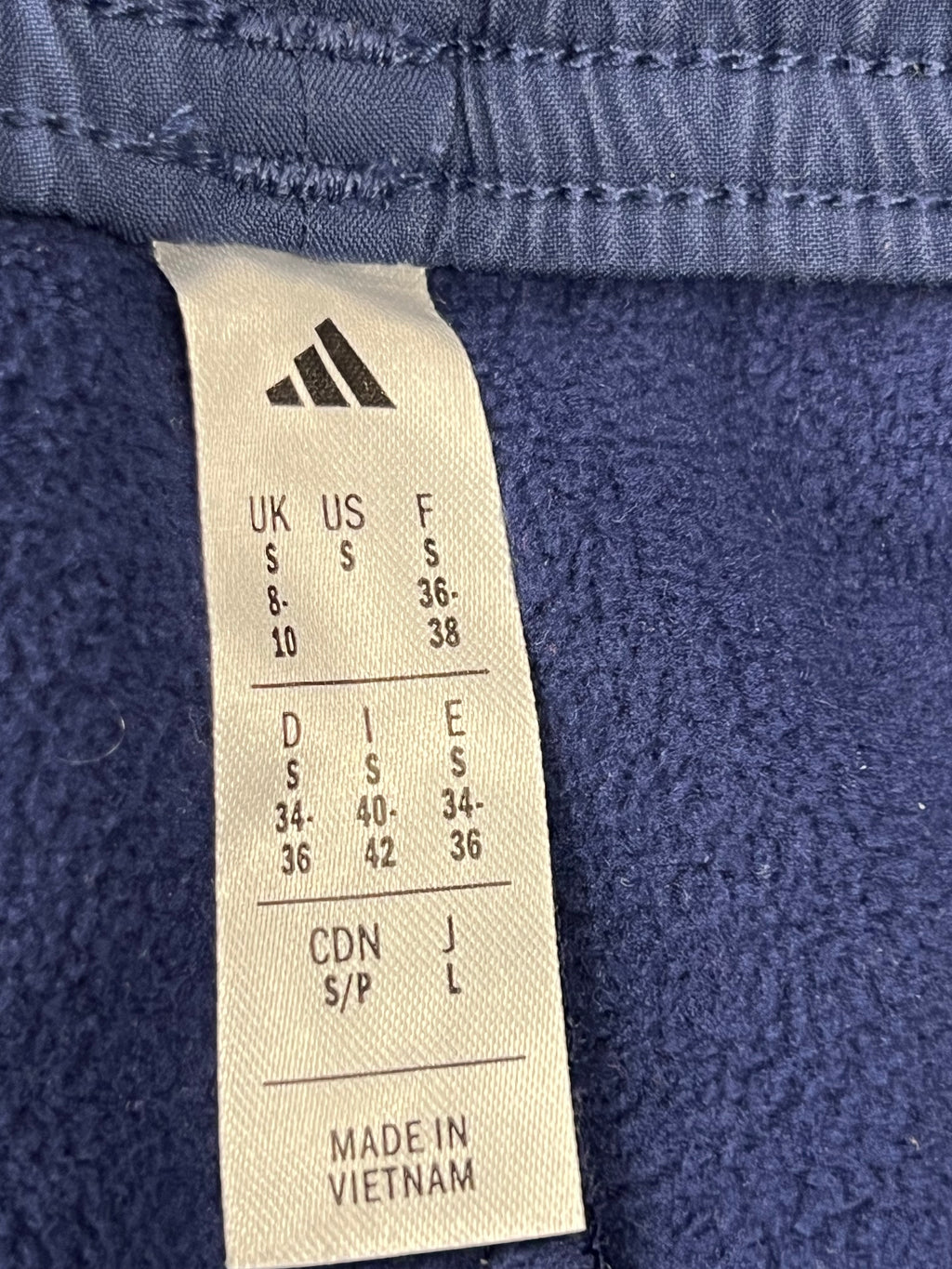 Close-up of adidas size label indicating UK size small and Made in Vietnam