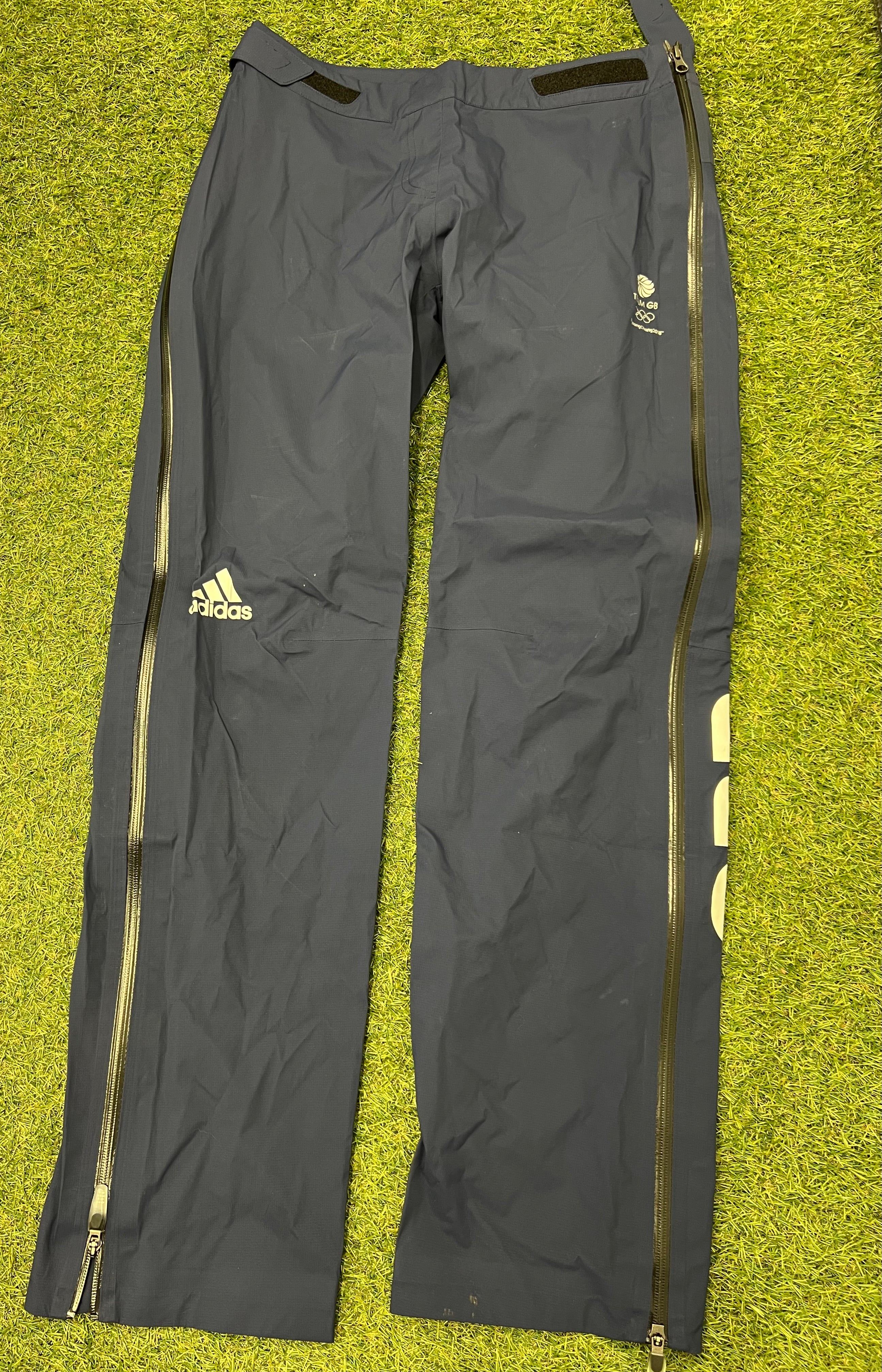 adidas Women's Team GB waterproof trousers laid flat on grass showing front with taped seams and logos