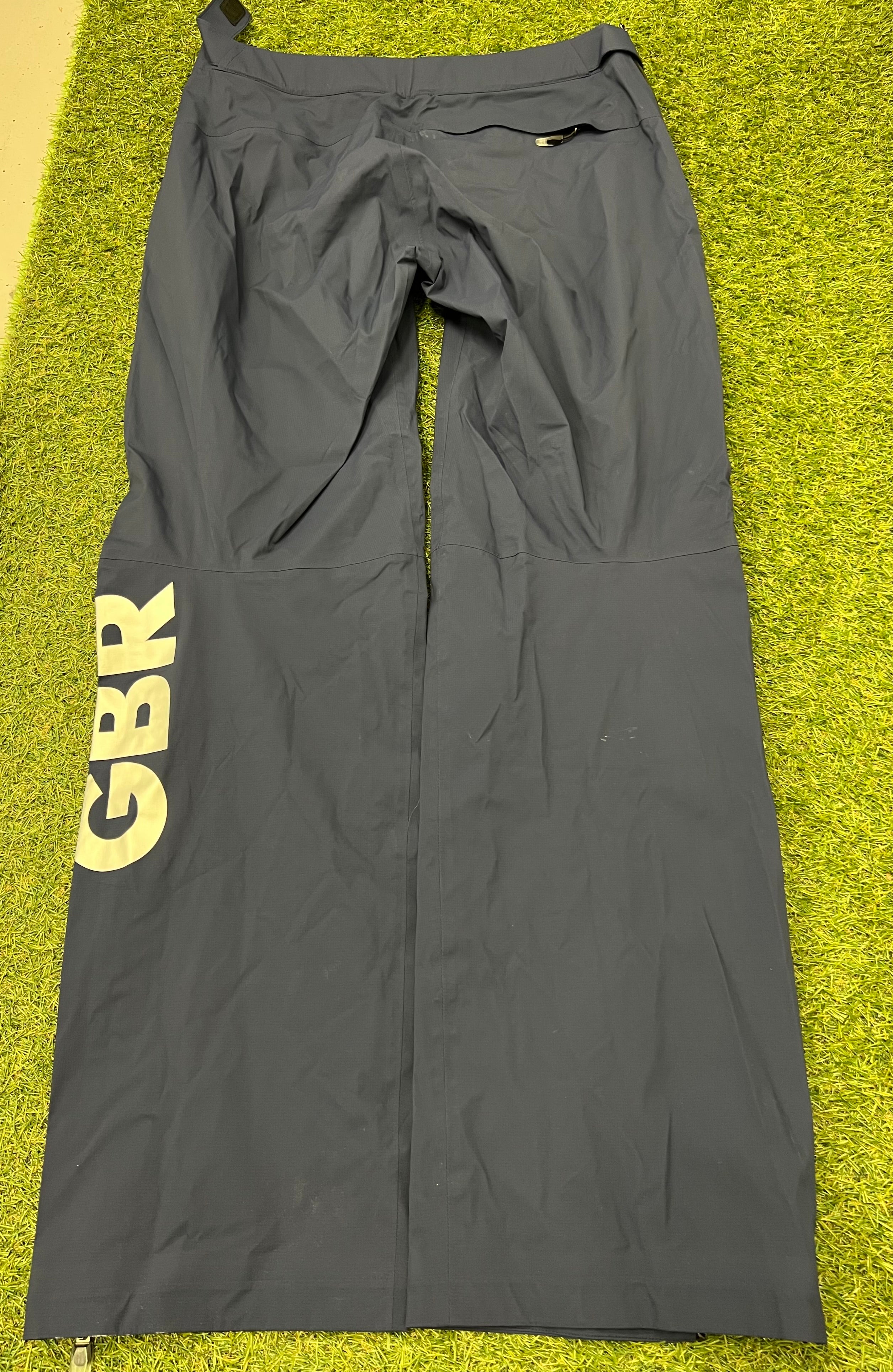 Back view of dark waterproof trousers with large 'GBR' lettering on the leg