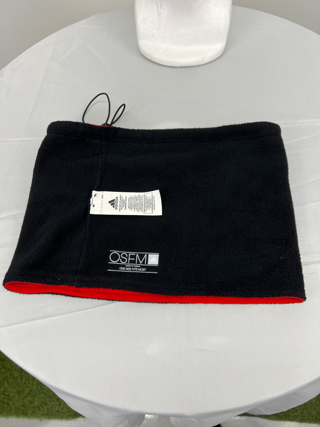 Red neck warmer with Team GB logo and Adidas patch on flat surface