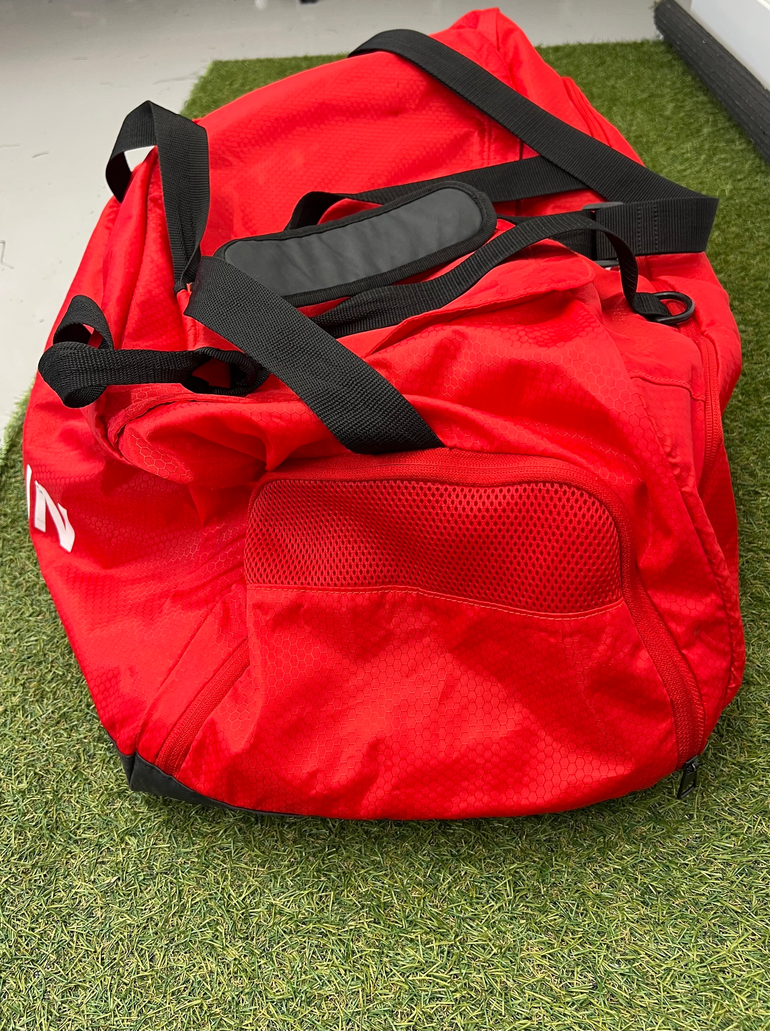 Side view of red Adidas bag with adjustable black shoulder strap and mesh pocket