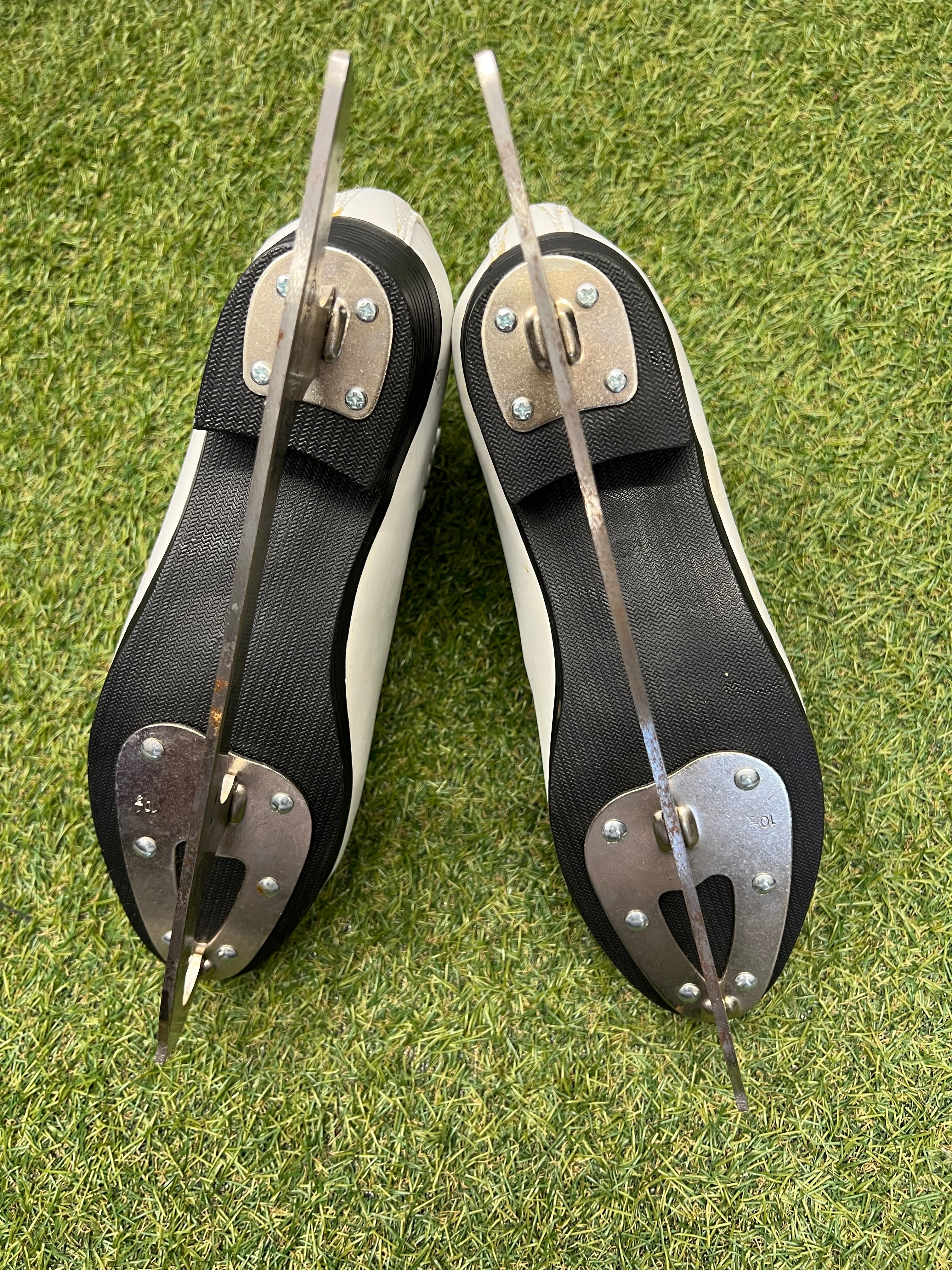 Bottom view of figure skates showing textured black soles and metal blades with Oxelo branding