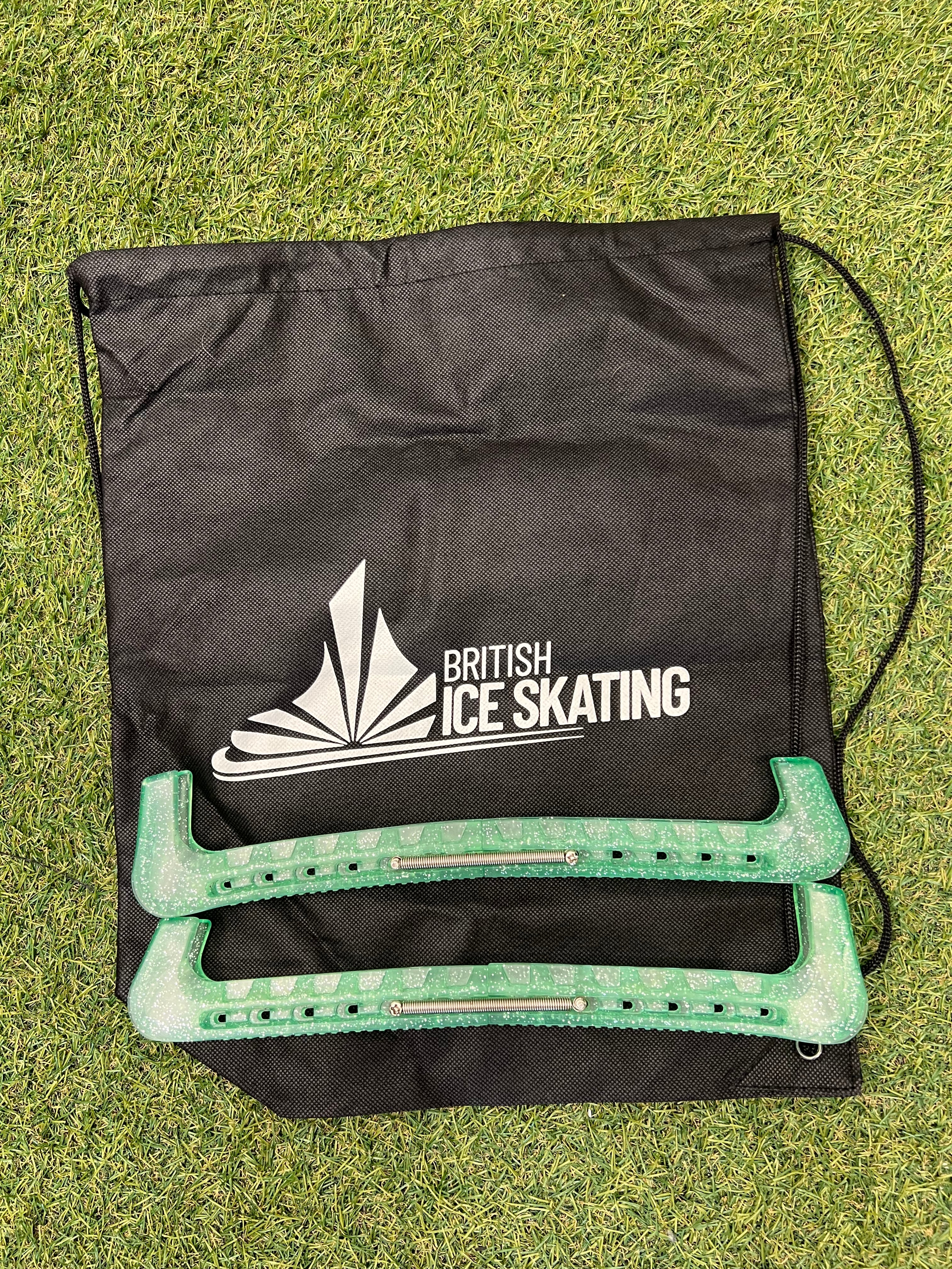 Green blade guards resting on British Ice Skating branded black storage bag