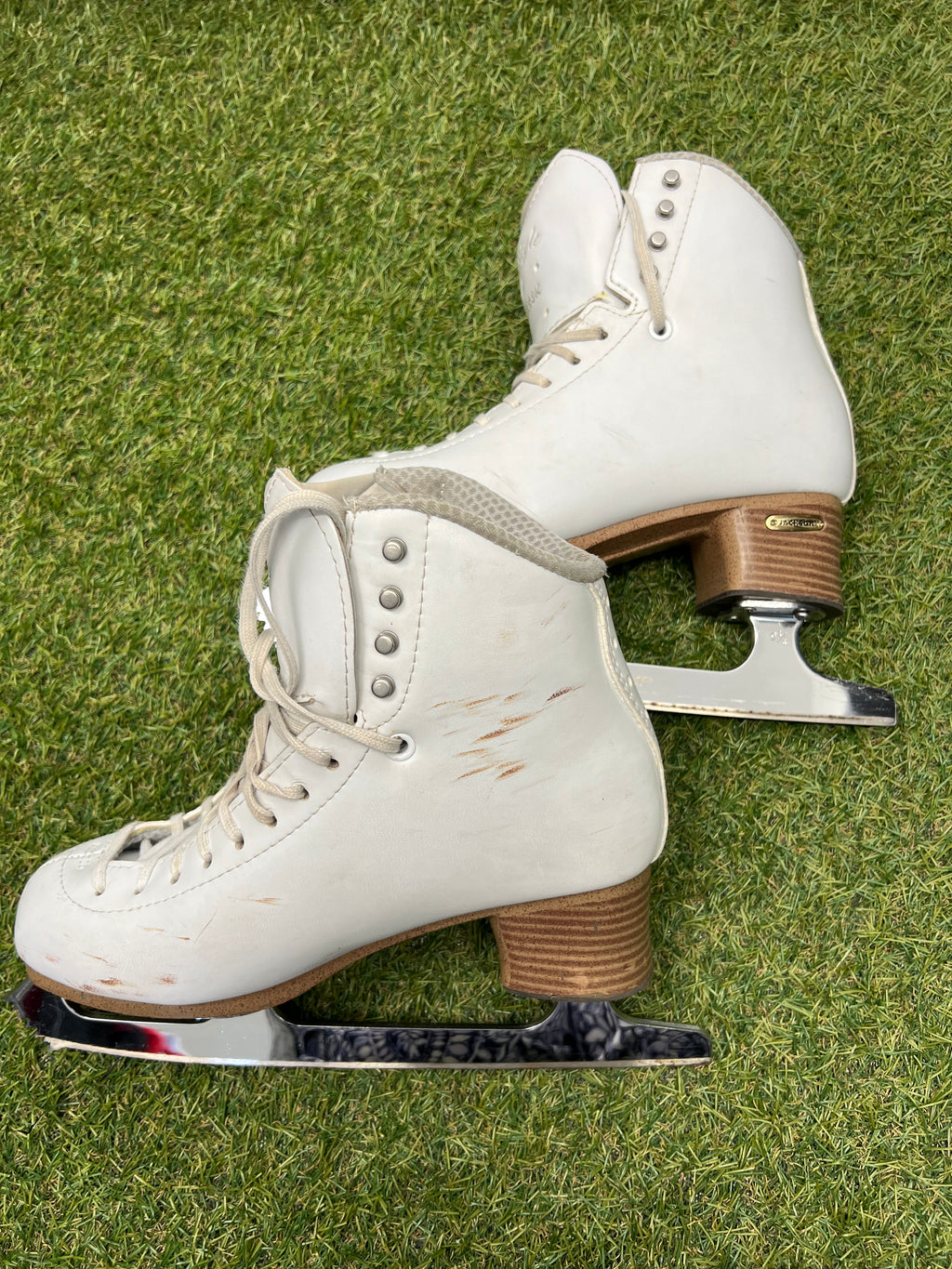 Side view of white leather figure skates showing lace holes and scuff marks