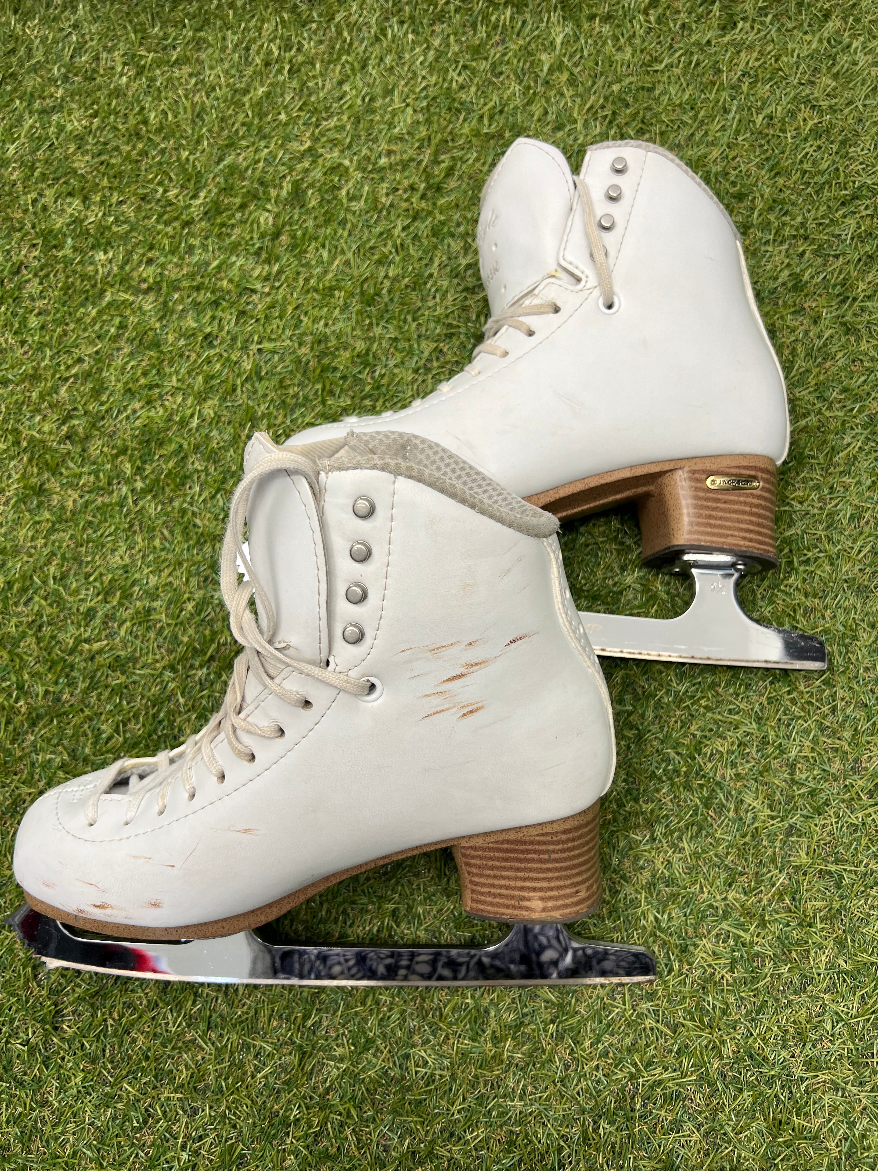 Side view of white leather figure skates showing lace holes and scuff marks