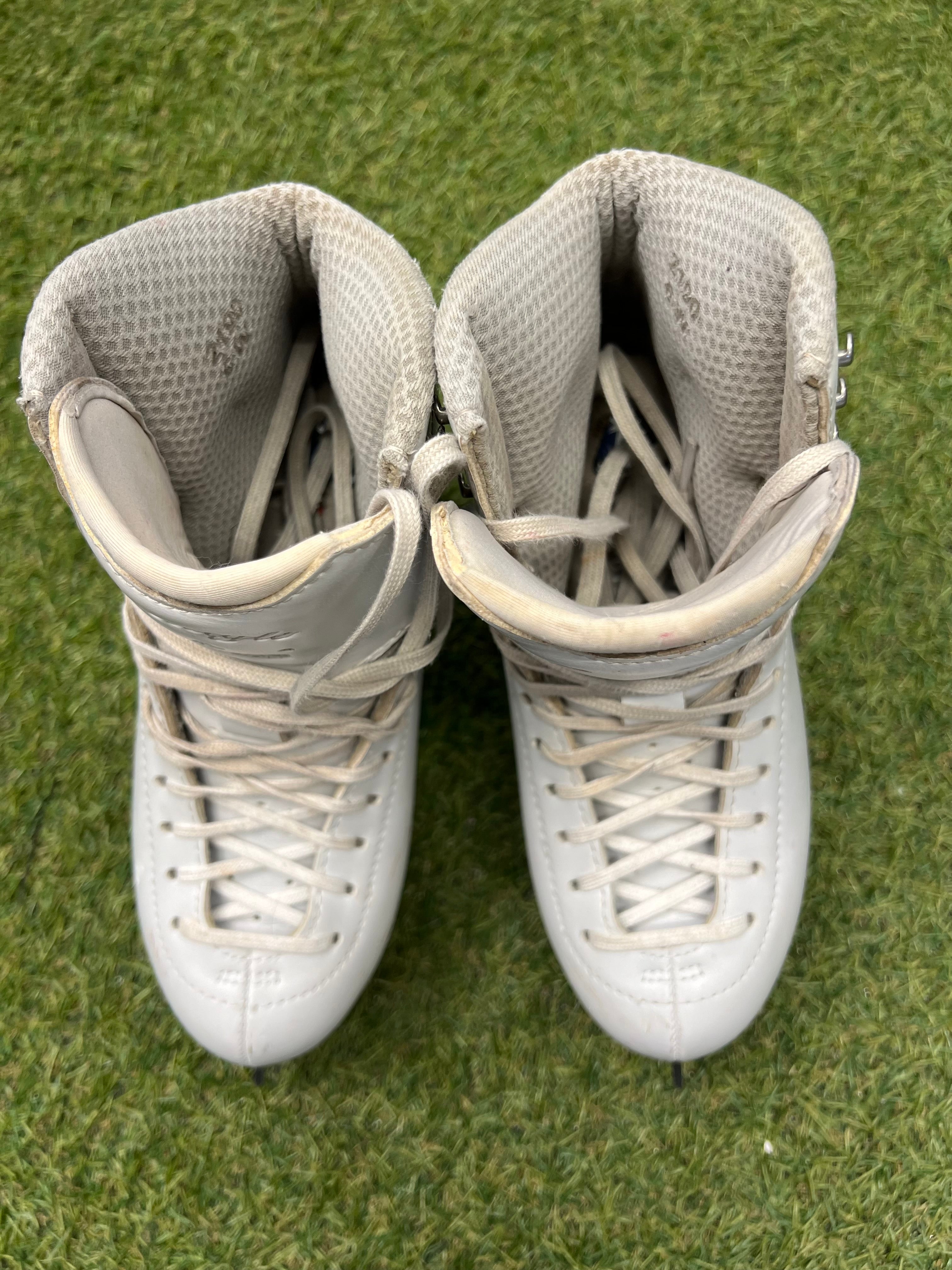 Top-down view of white figure skates with laces tied and padded liners visible