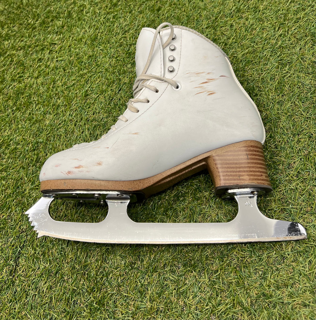 Side profile of white figure skate with clear view of sturdy heel and blade details
