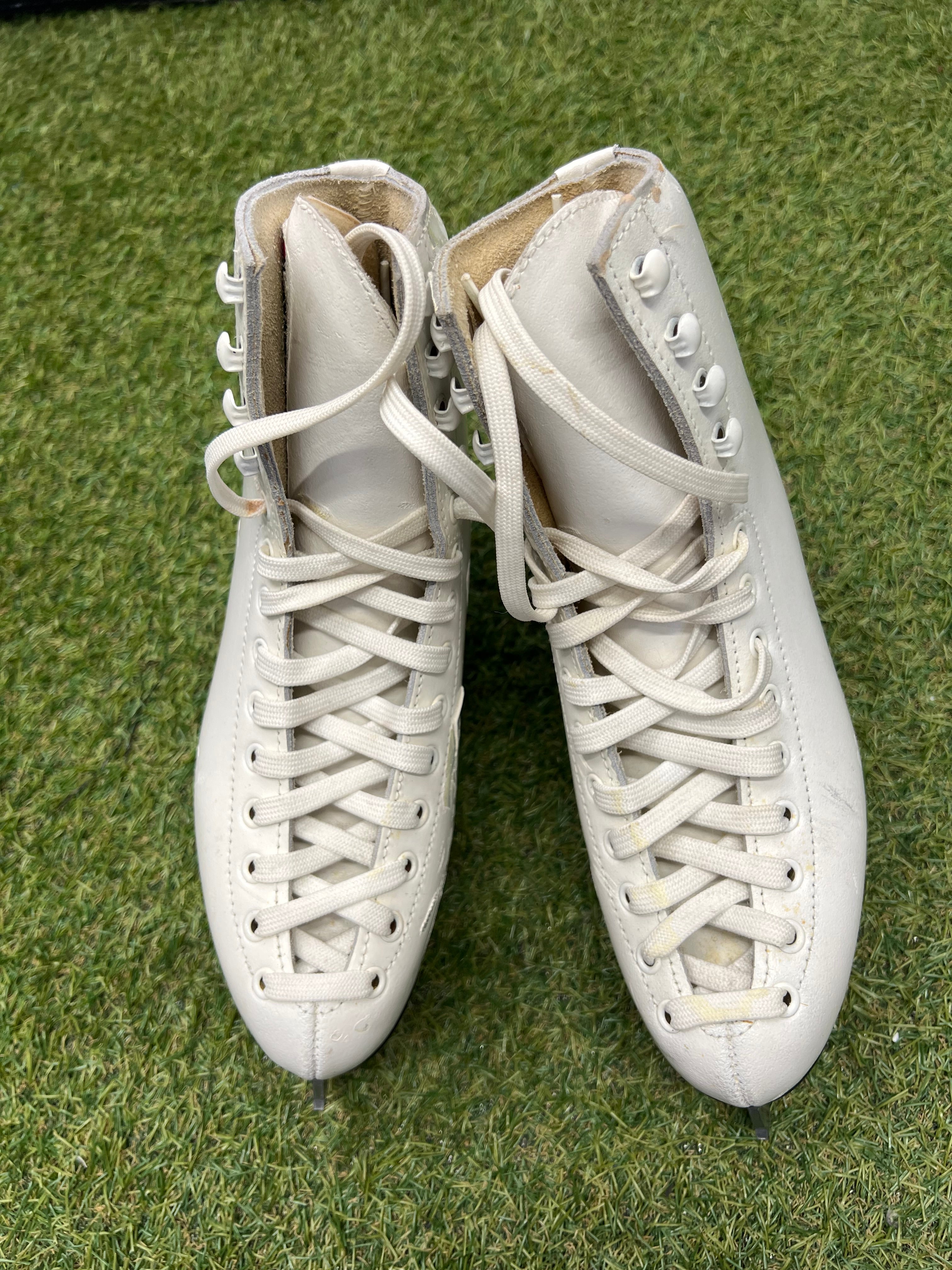Top view of classic white women's figure skates with laces tied on grass background