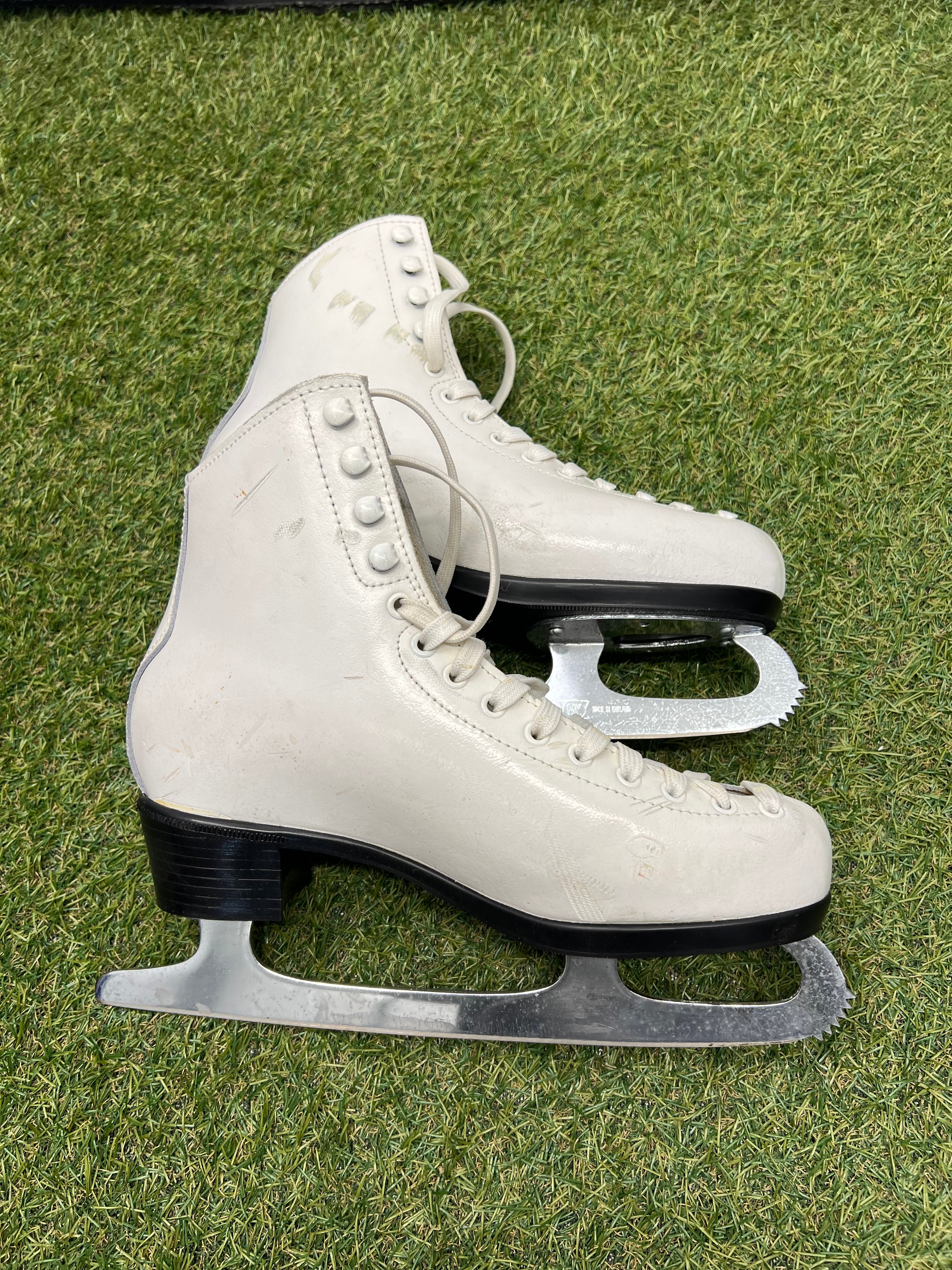 Opposite side view of white leather figure skates highlighting lace hooks and support