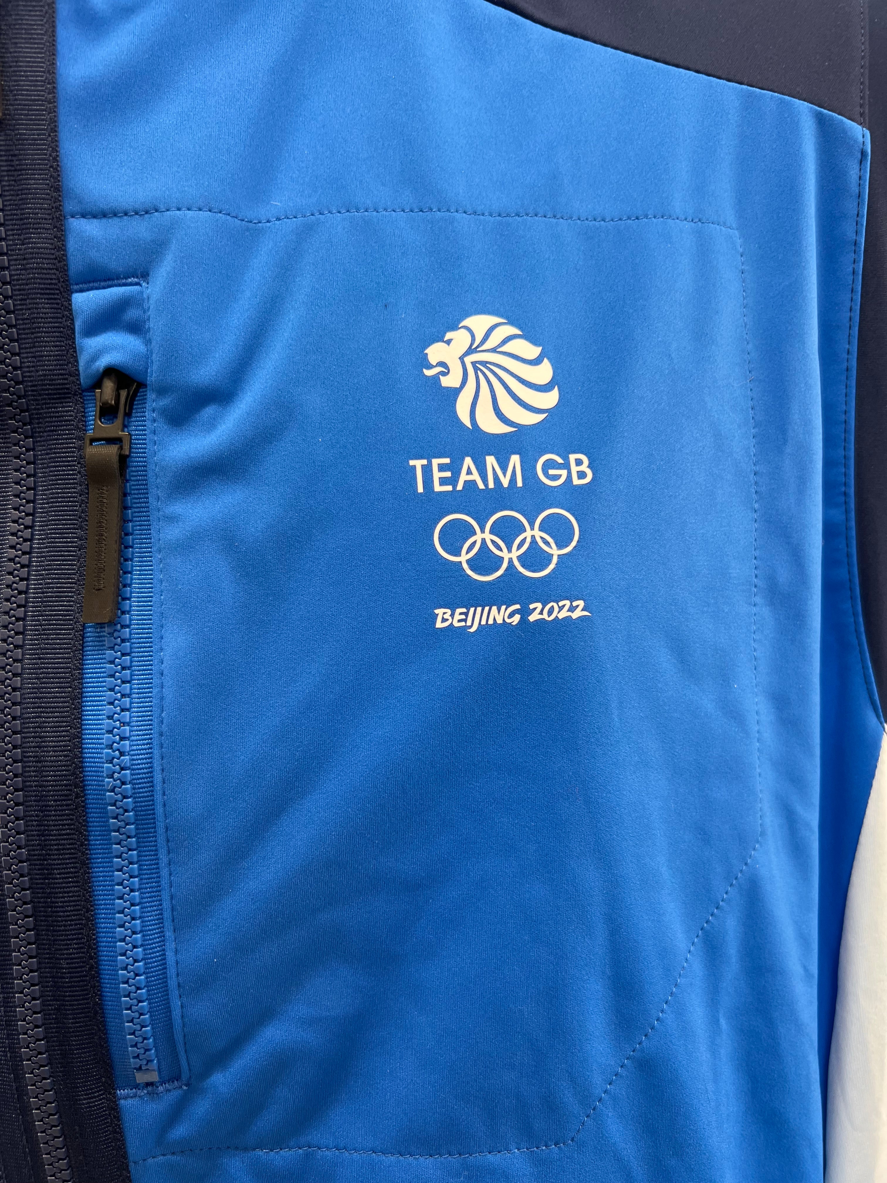 Close-up of Team GB lion logo, Olympic rings, and Beijing 2022 print on blue panel with zip pocket