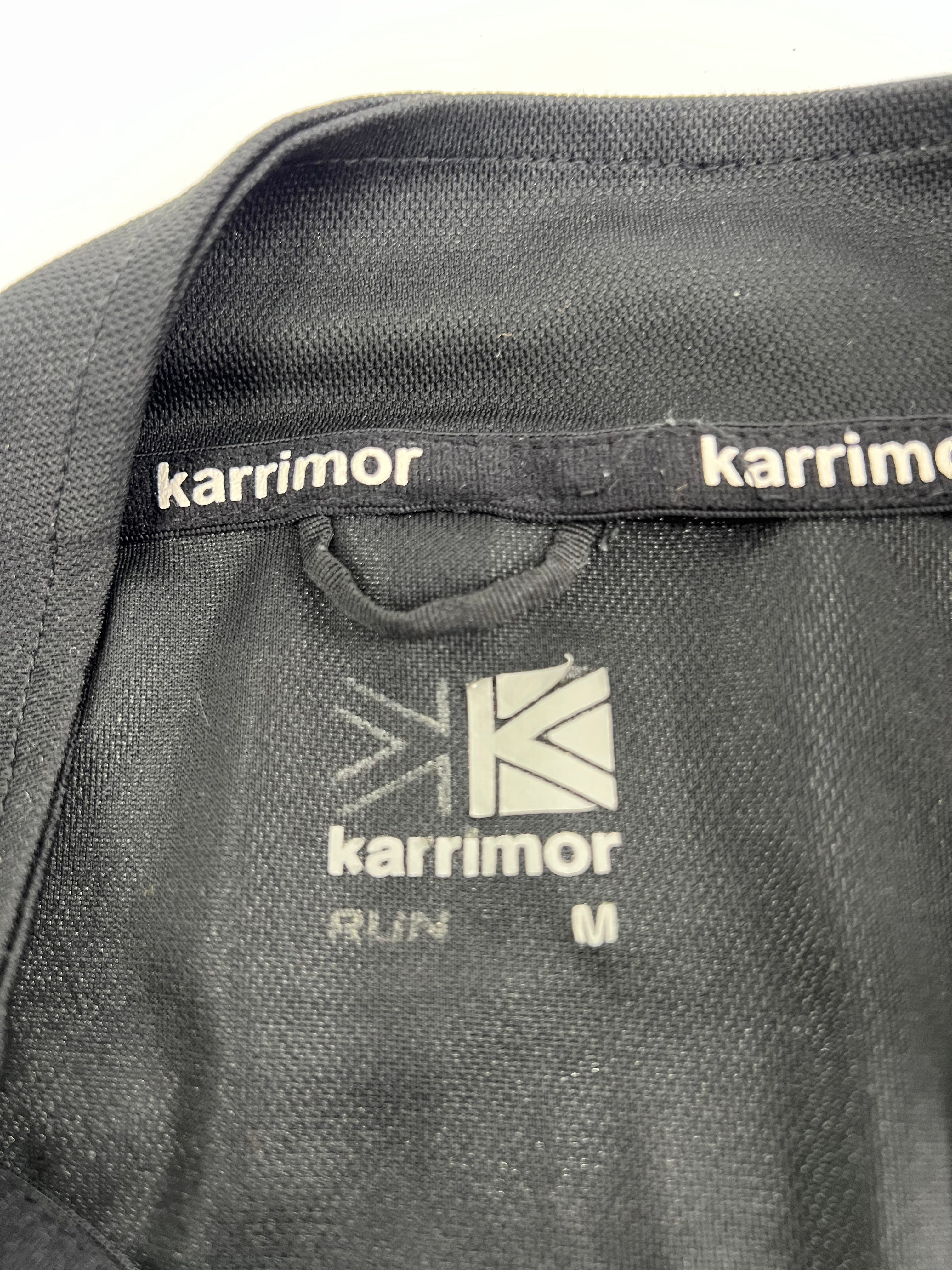Close-up of Karrimor label inside black running half-zip top with size and branding