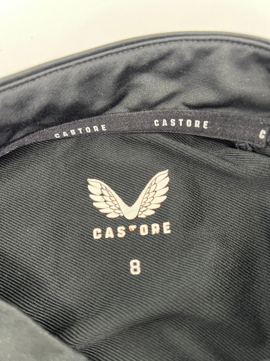 Close-up inside label of Castore Harlequins women's training top showing brand logo and size 8