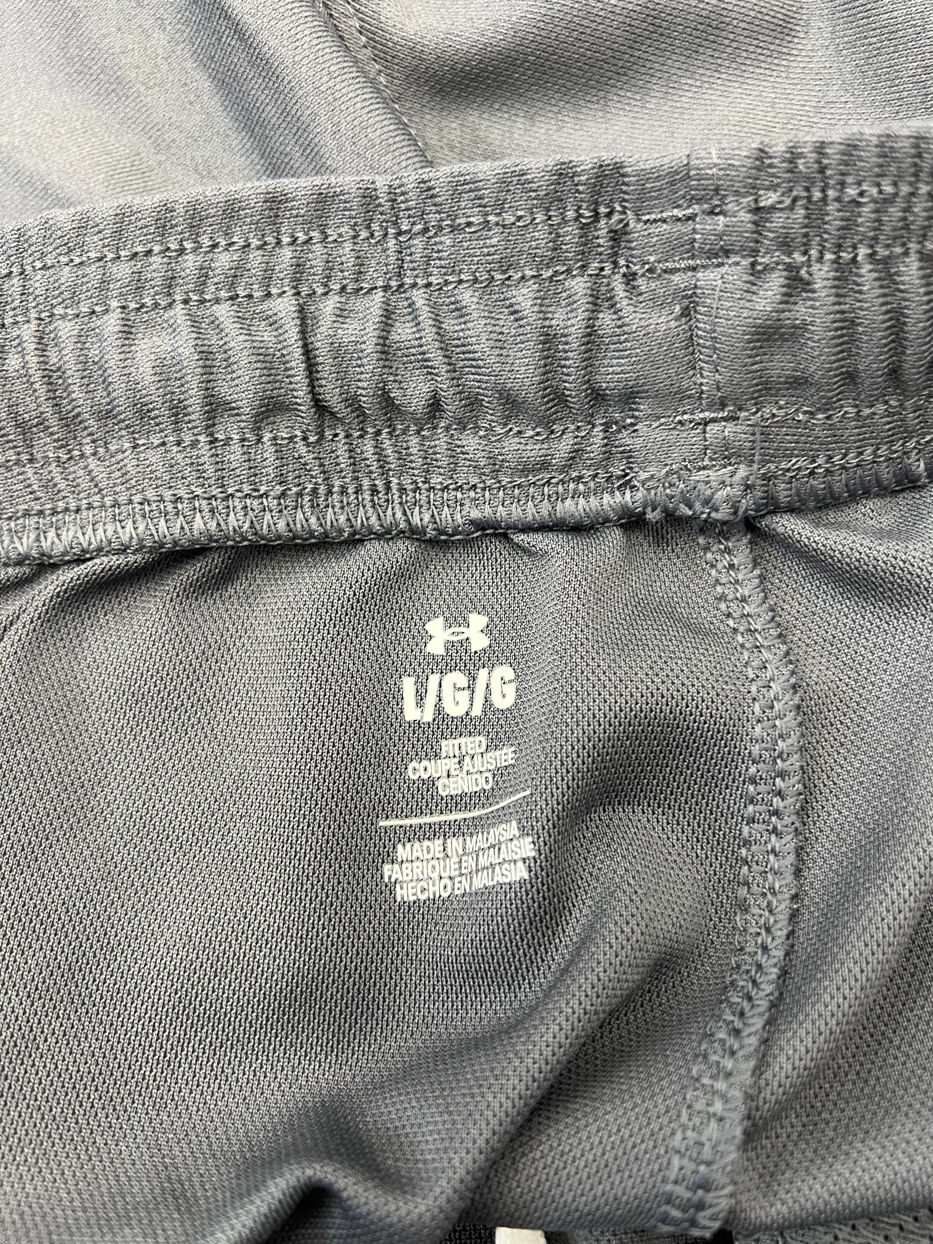 Close-up of Under Armour label inside waistband on fitted grey tracksuit bottoms