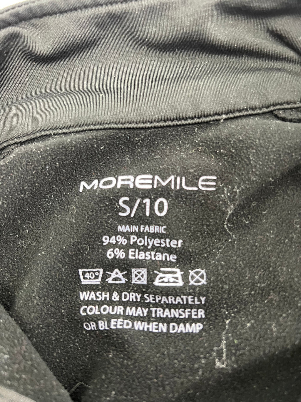 Close-up of fabric care label showing 94% polyester 6% elastane material composition