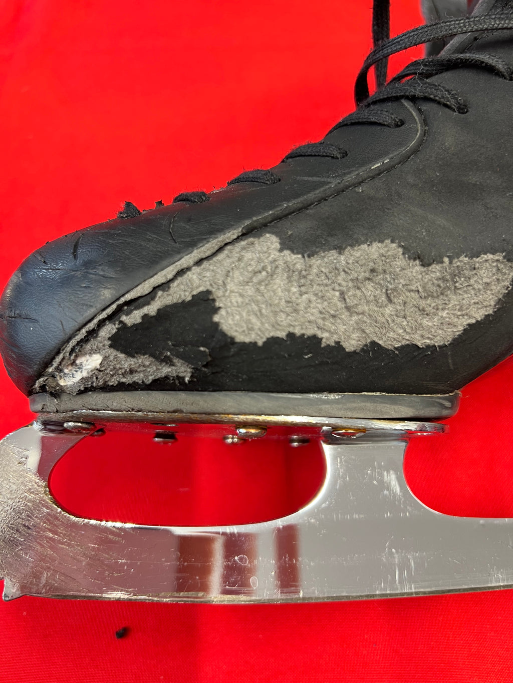 Detailed close-up of scuffed leather on boot toe area with visible wear on blade attachment