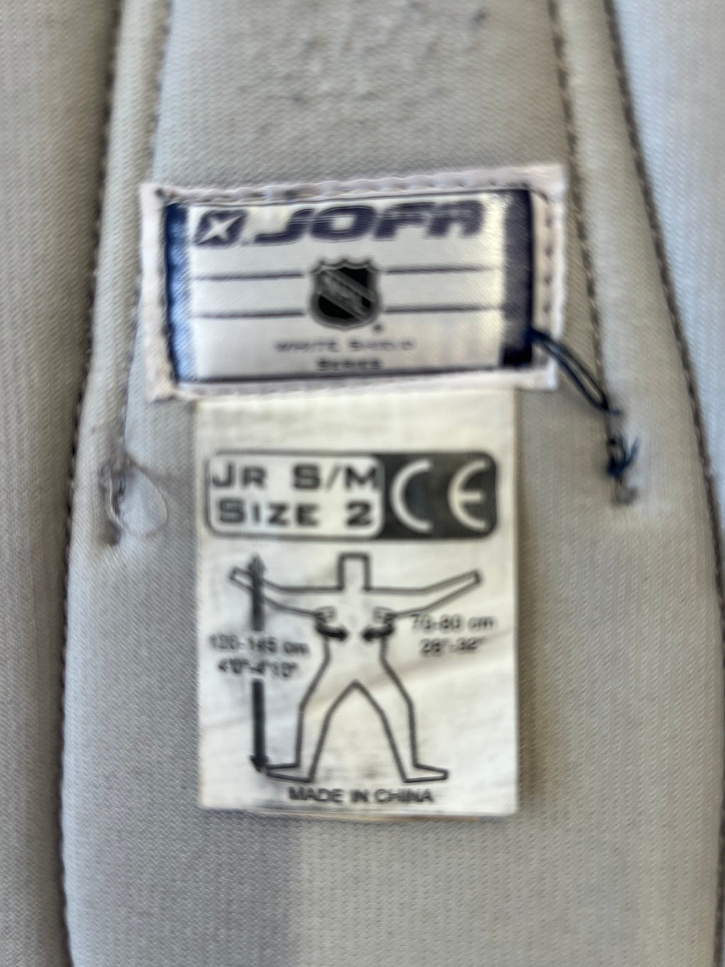 Close-up of JOFA NHL White Shield Series label showing size Jr S/M and product details
