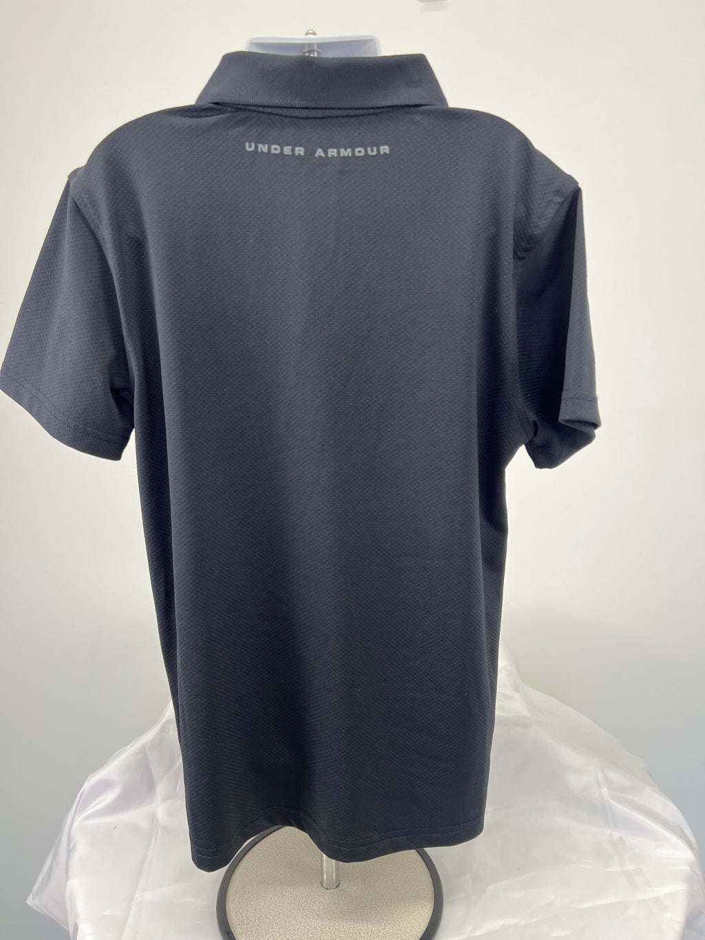Back view of black Under Armour youth polo shirt with branded text