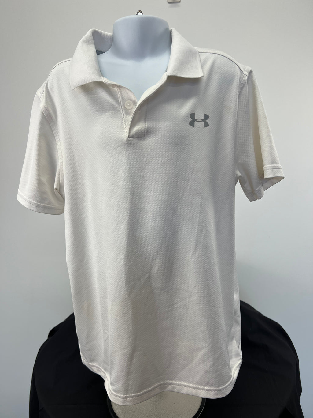 Front view of white Under Armour youth polo shirt with logo on chest