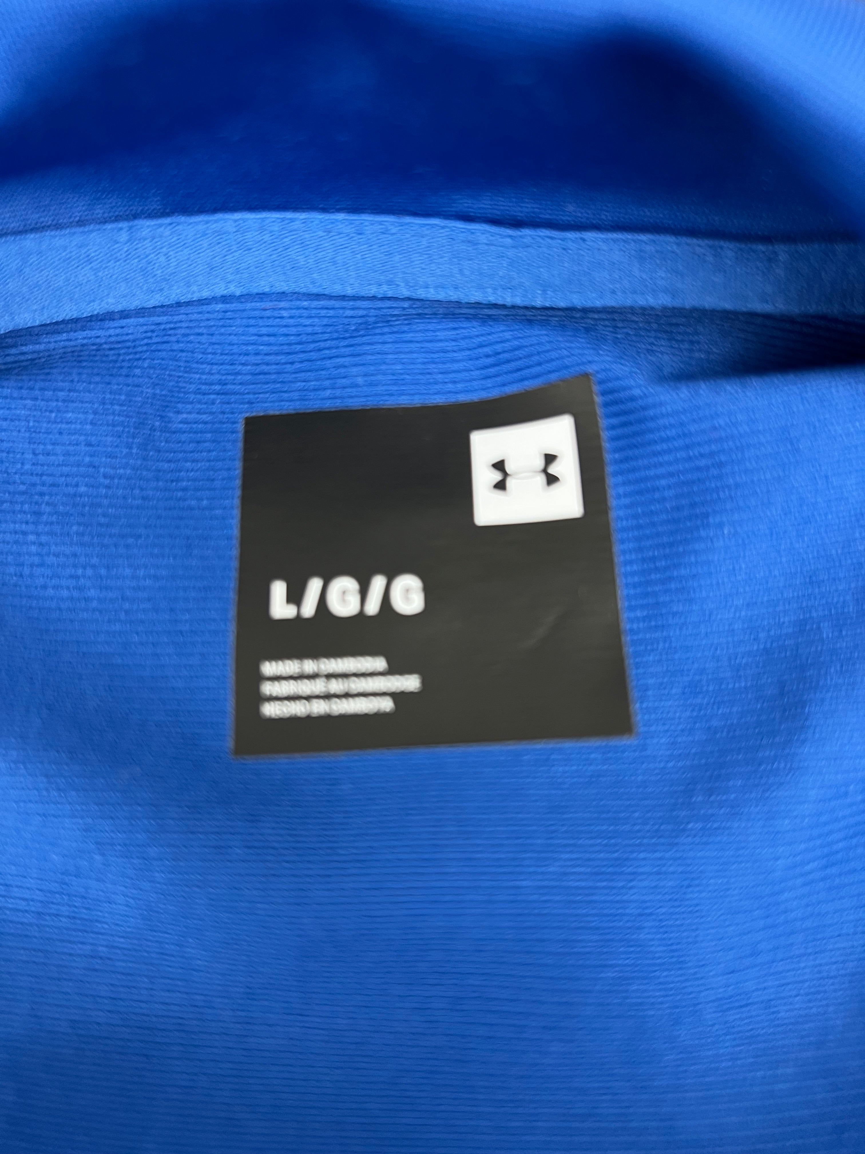 Close-up of size tag inside men's Under Armour blue track jacket showing large size