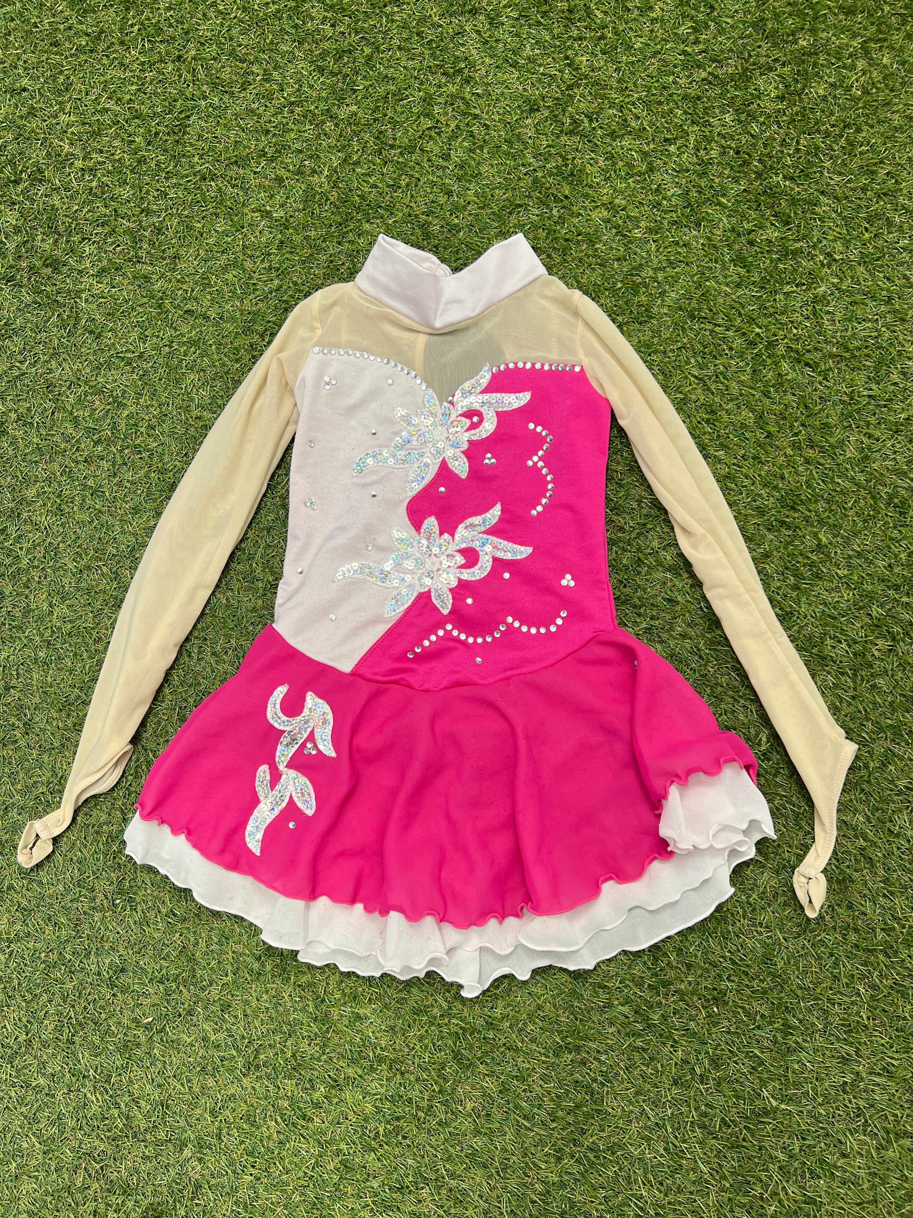 Front view of pink and cream long sleeve embellished kids ice skating dress with floral rhinestones and ruffled skirt