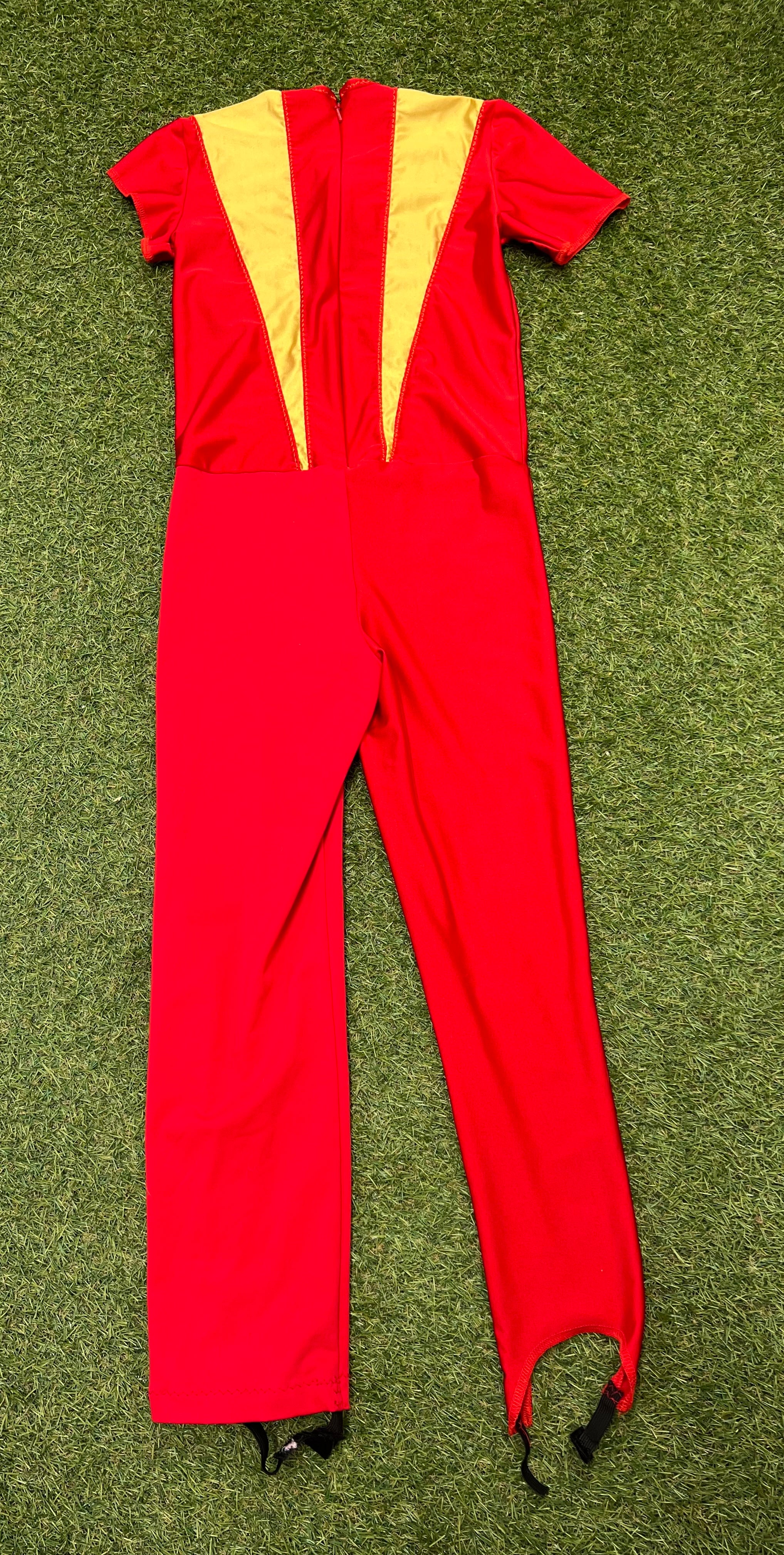 Back view of red kids ice skating jumpsuit with yellow and dark red panels and zipper closure