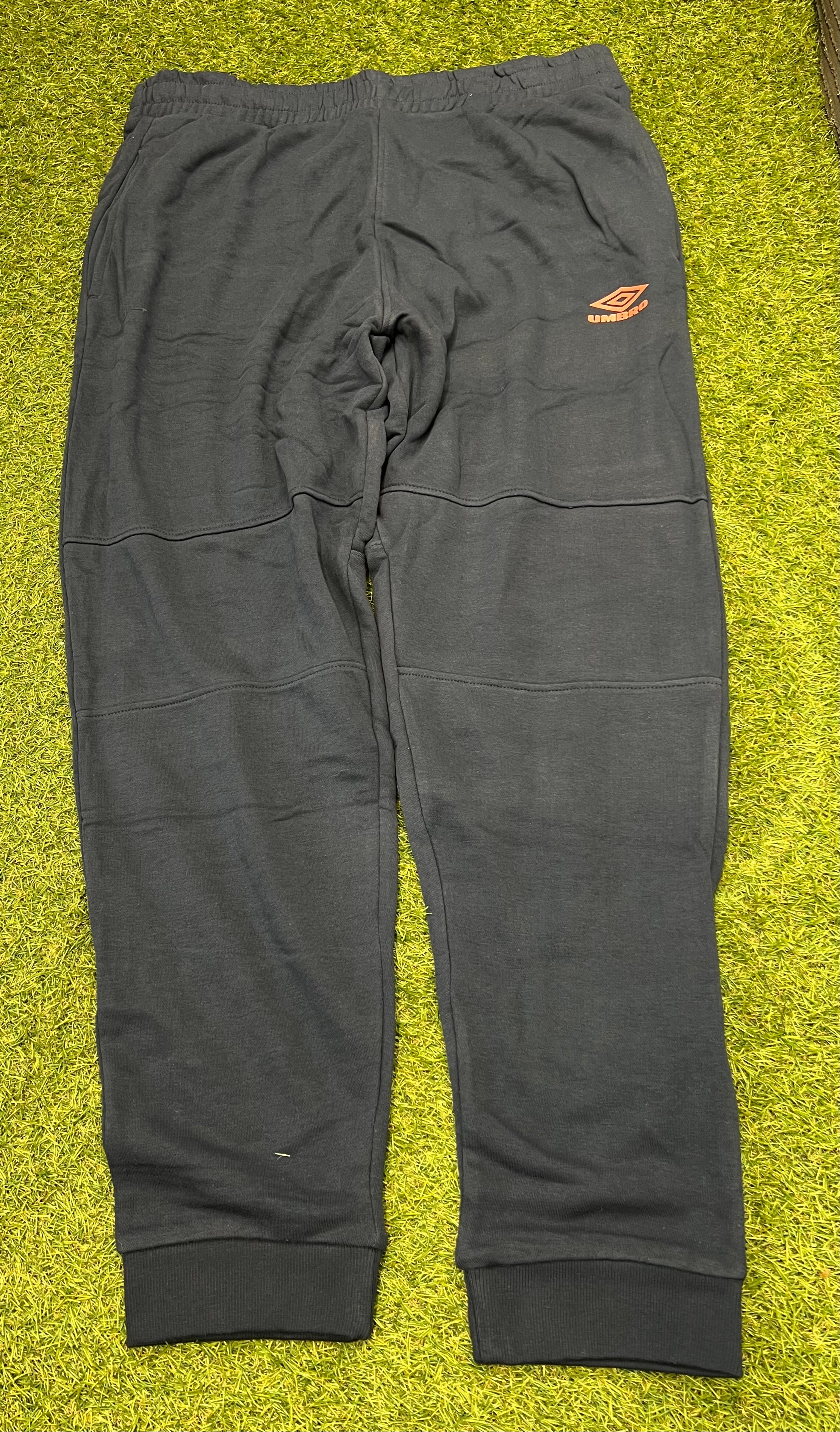 Front view of men’s black Umbro diamond skinny jog pants with orange logo on thigh